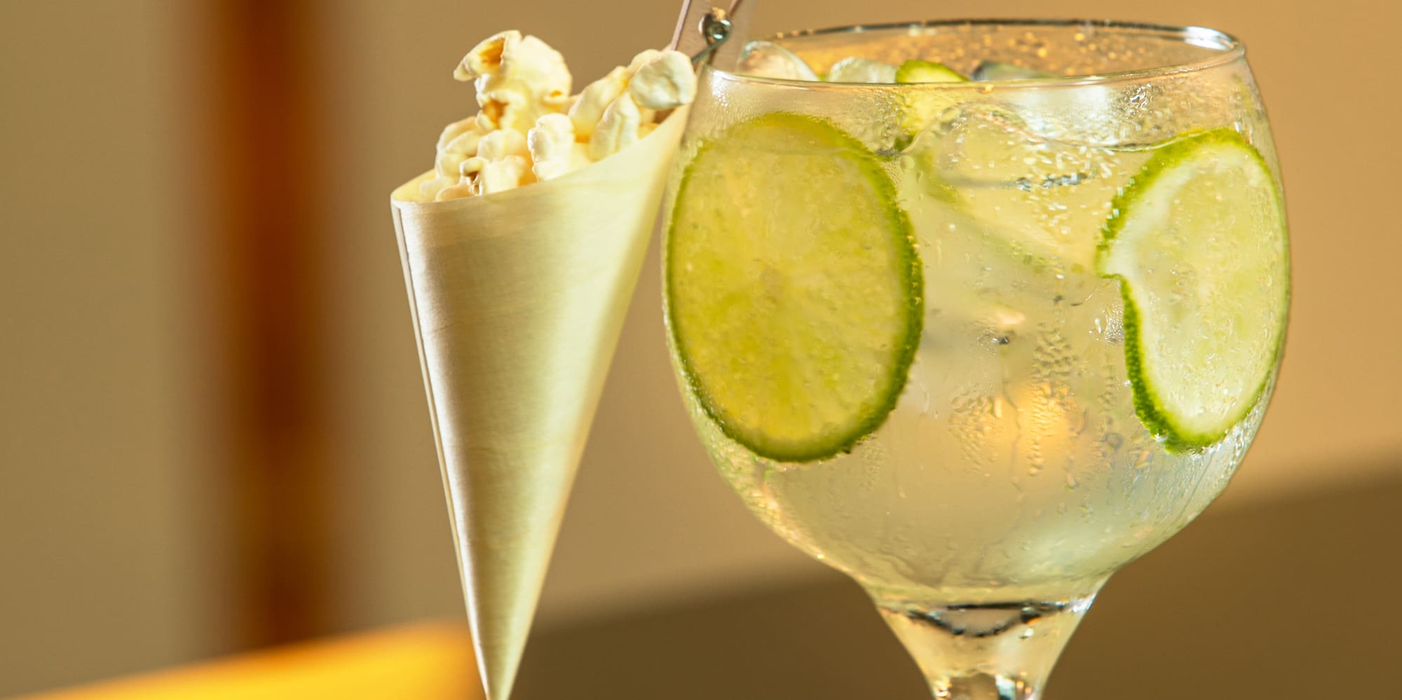 a glass of liquid with ice and popcorn in a cone