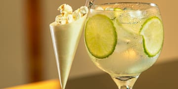 a glass of liquid with ice and popcorn in a cone