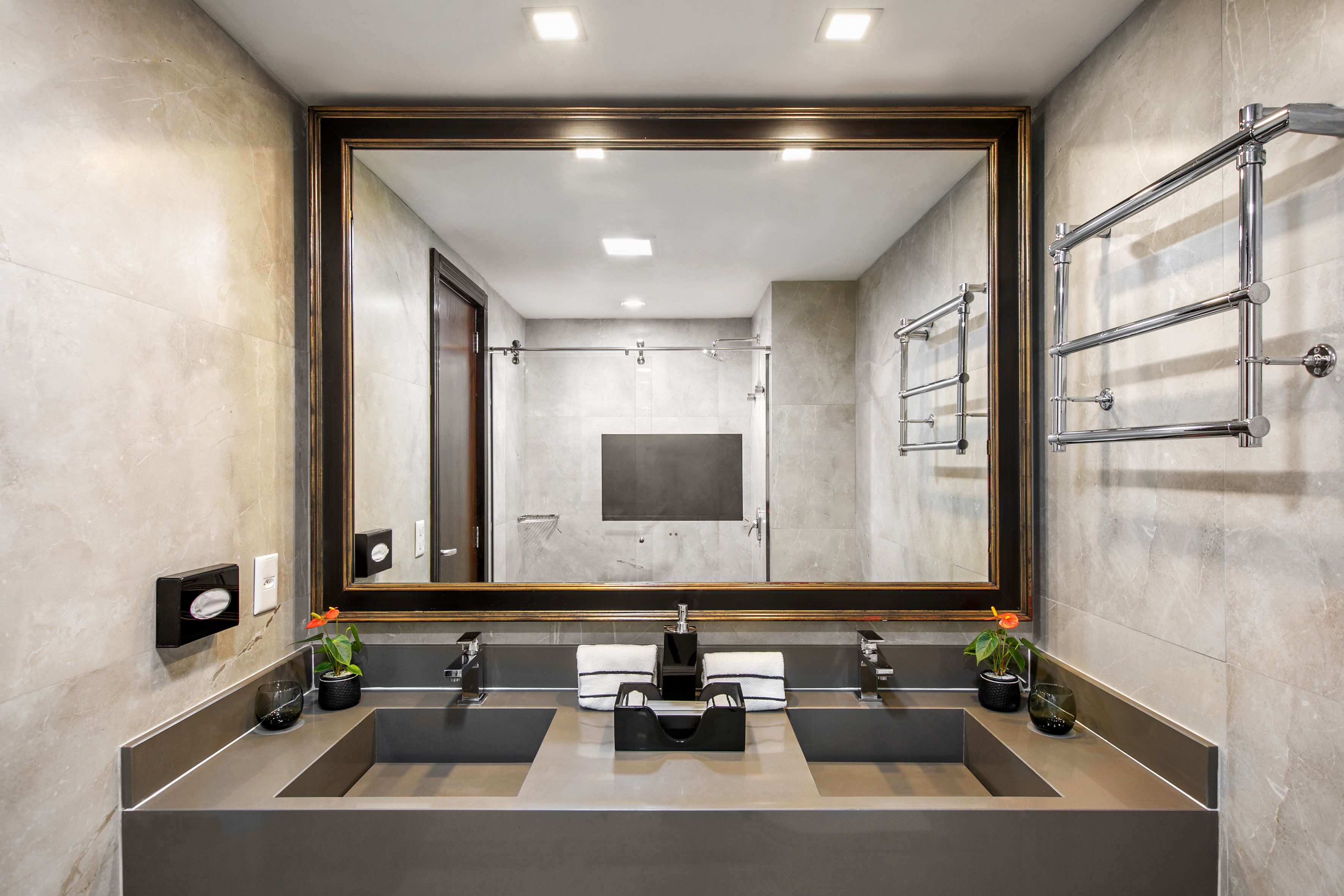 Luxury modern bathroom, dual sink vanity with framed mirror and marble walls.