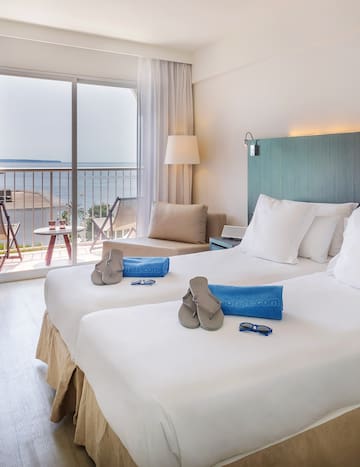 a room with two beds and a balcony overlooking the ocean