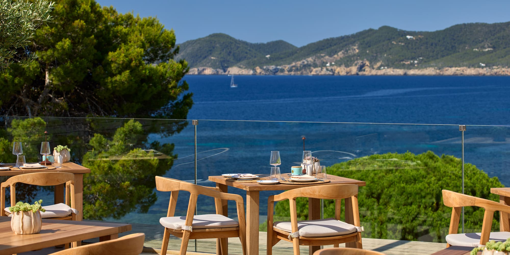 Outdoor restaurant terrace with sea views and wooden furniture.