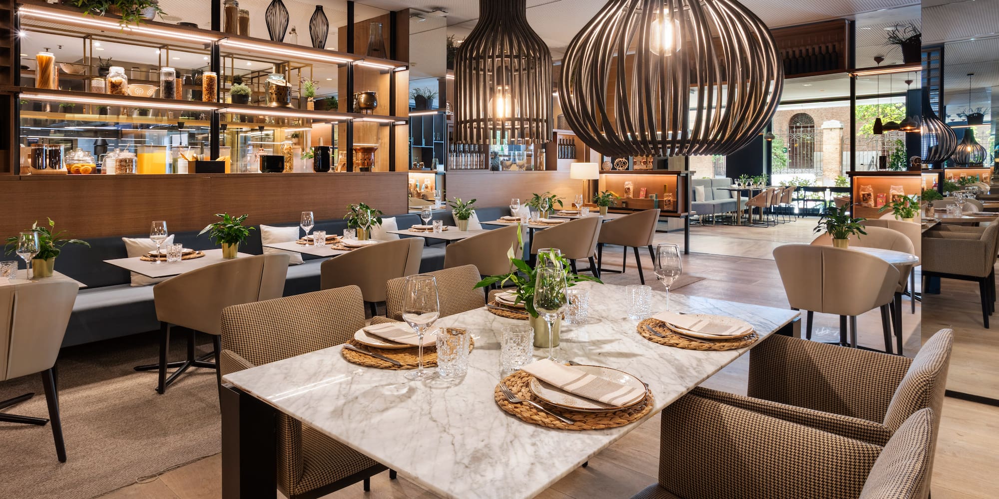 Modern restaurant interior with dining tables, booth seating, and large pendant lights.