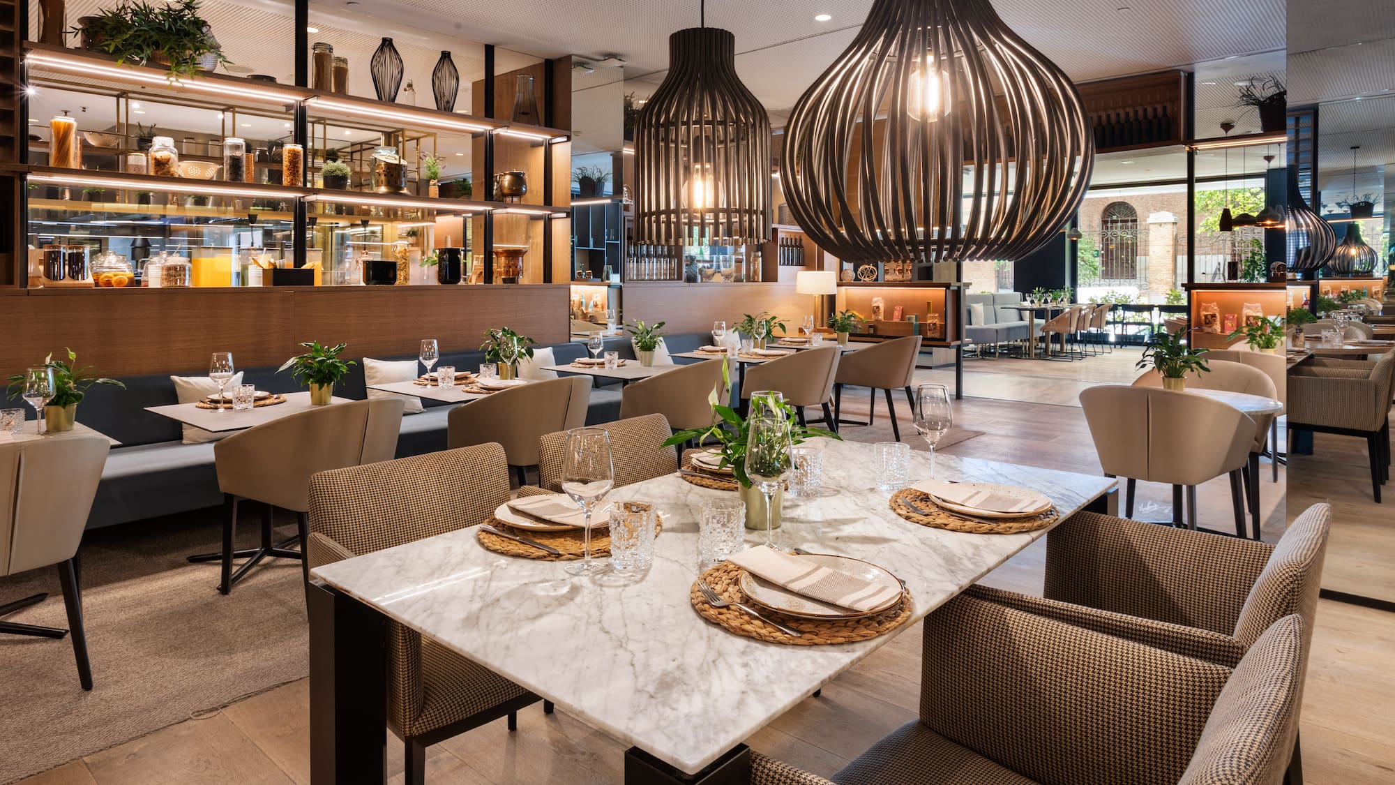 Modern restaurant interior with dining tables, booth seating, and large pendant lights.