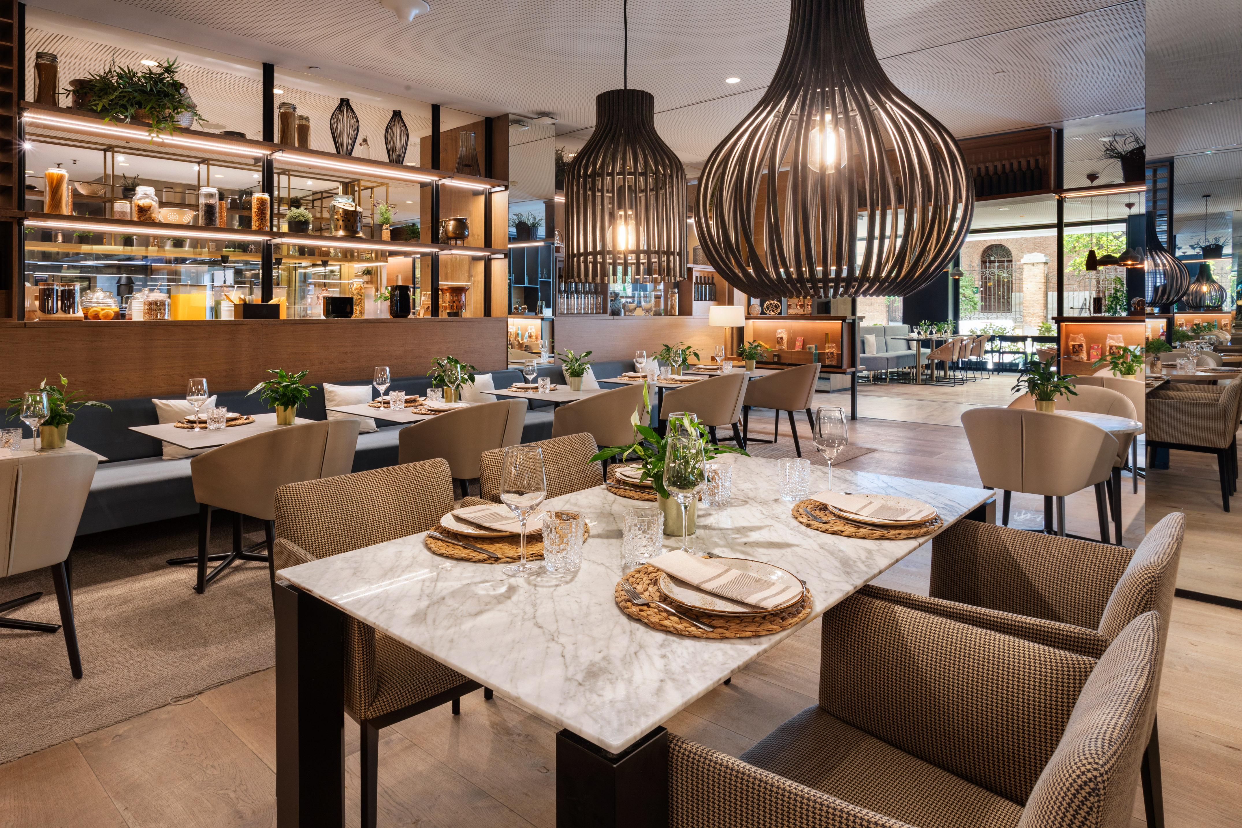 Modern restaurant interior with dining tables, booth seating, and large pendant lights.