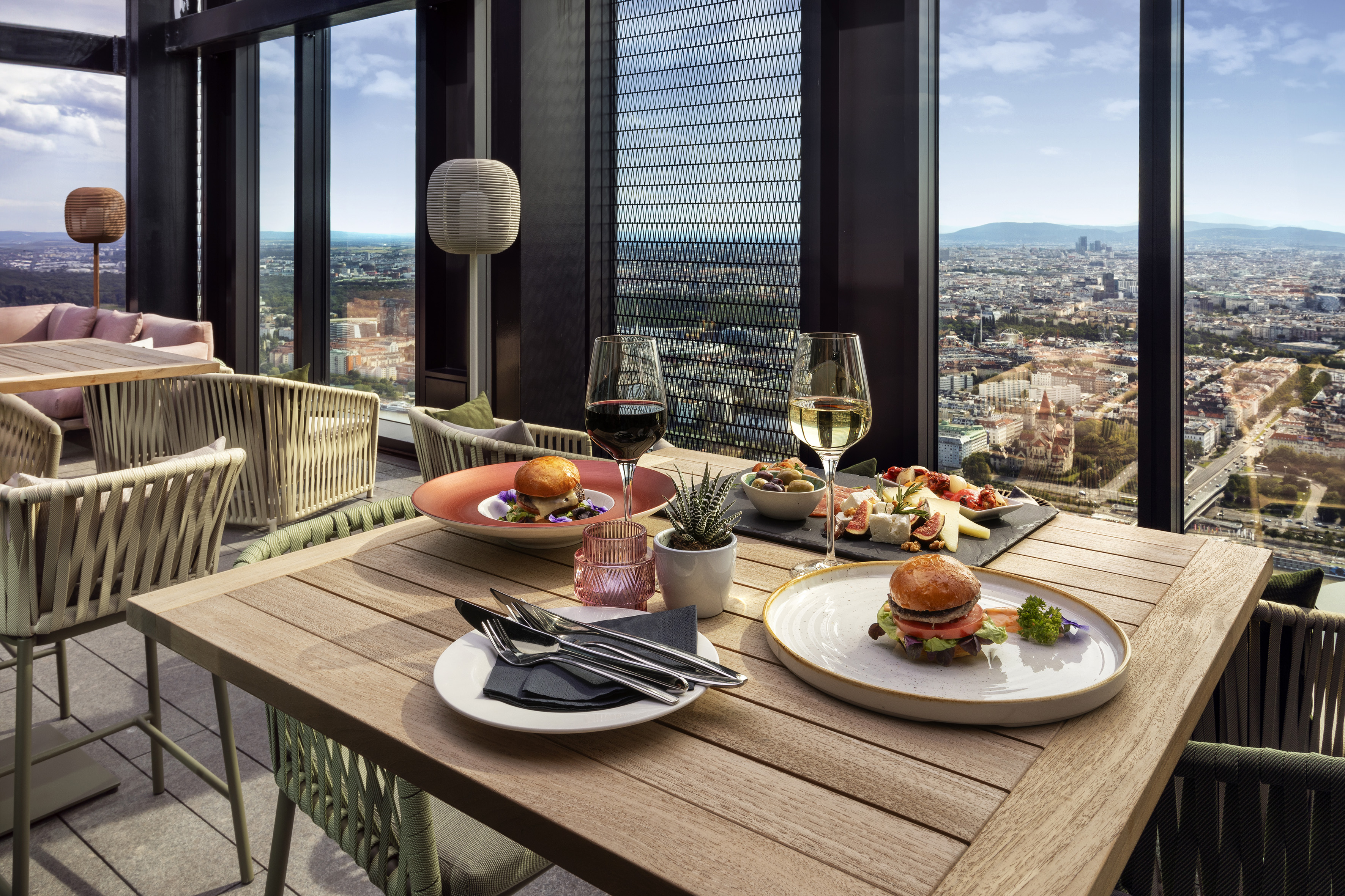 High-rise balcony dining with gourmet burgers, wine, and panoramic city views.