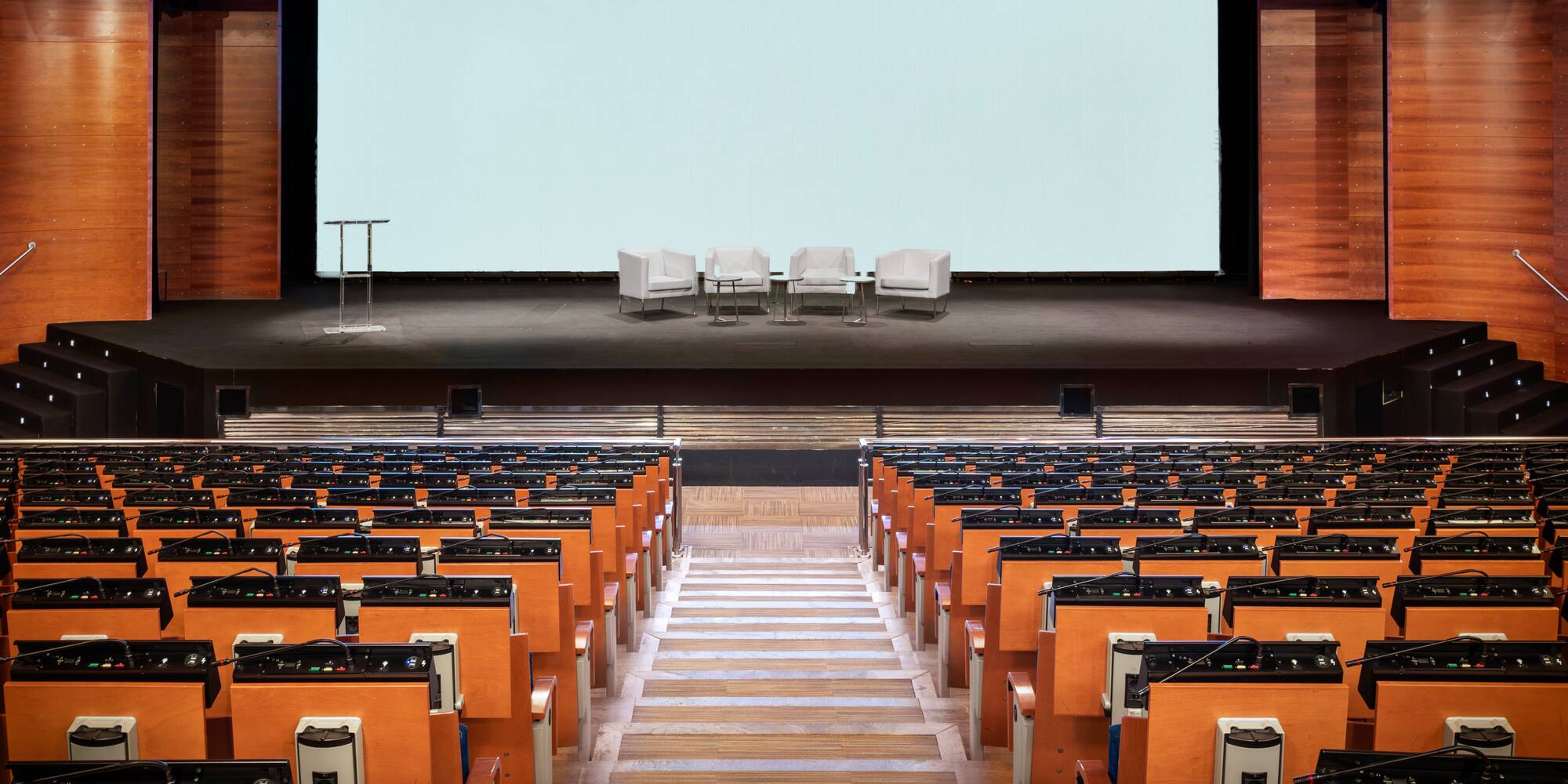 a stage with chairs and a large screen