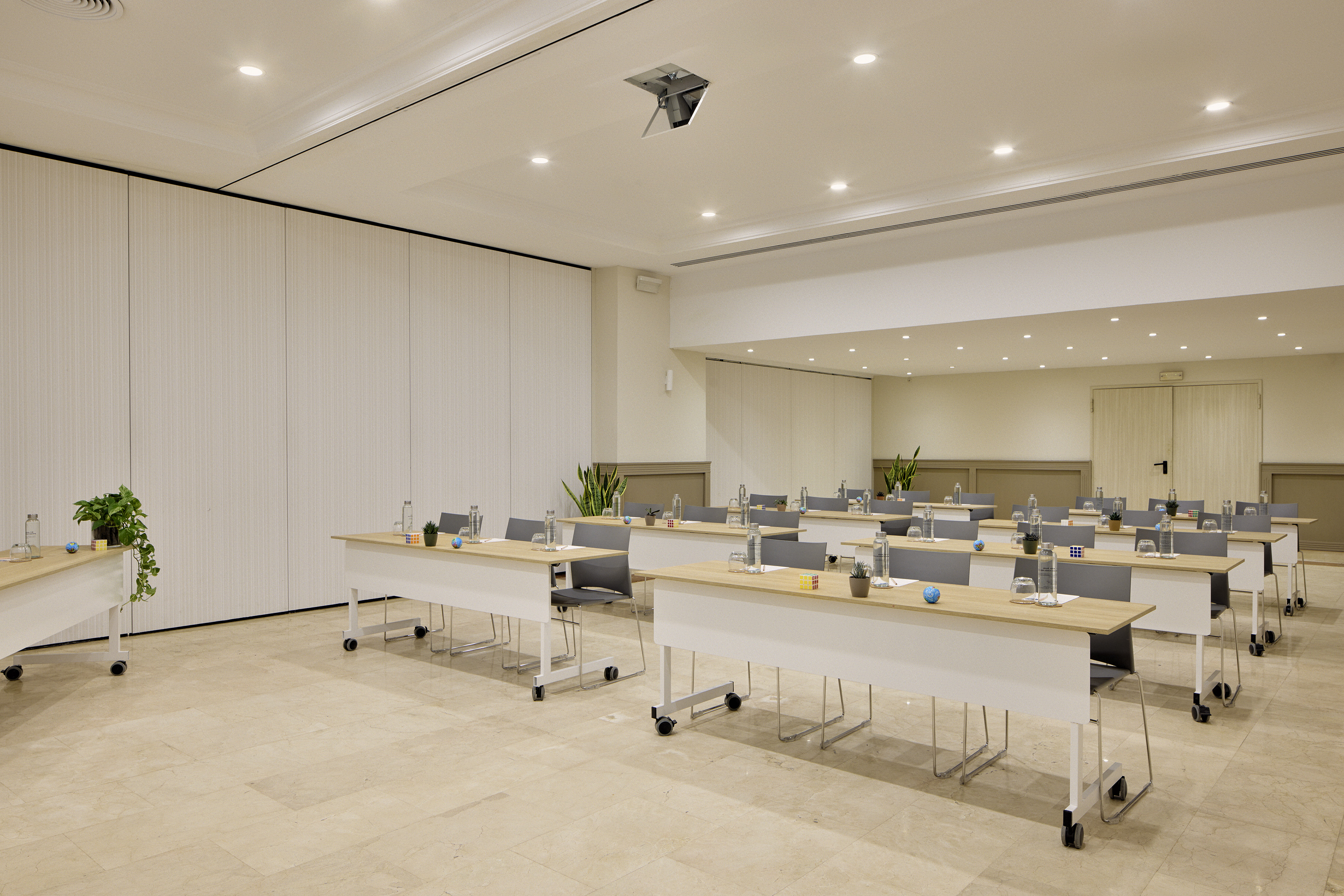 Empty modern meeting room with flexible tables, chairs, and ceiling projector.