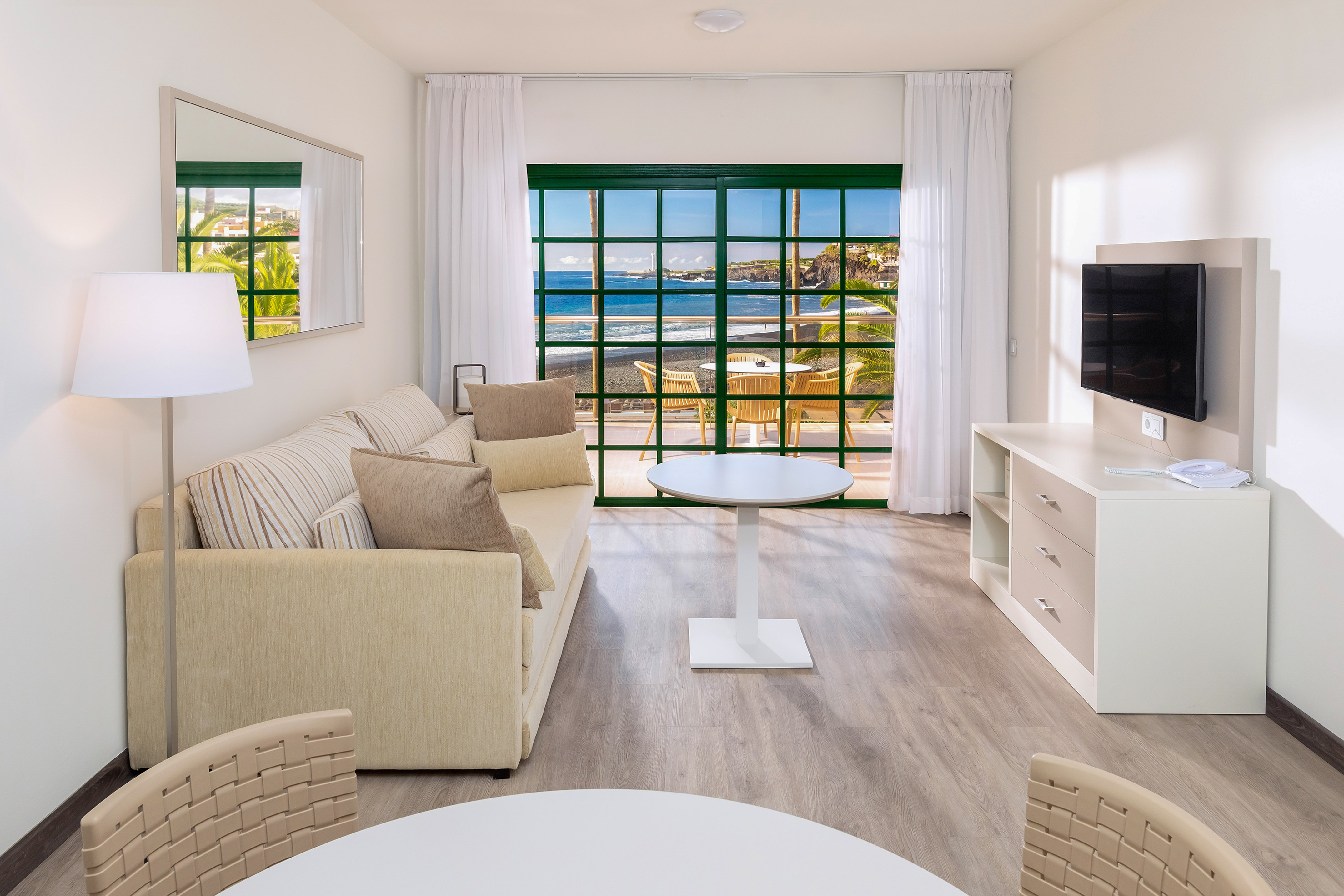 Coastal apartment living room with ocean view balcony, beige sofa, TV.