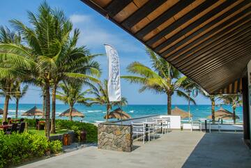 a patio with a white flag and chairs and a beach in the background