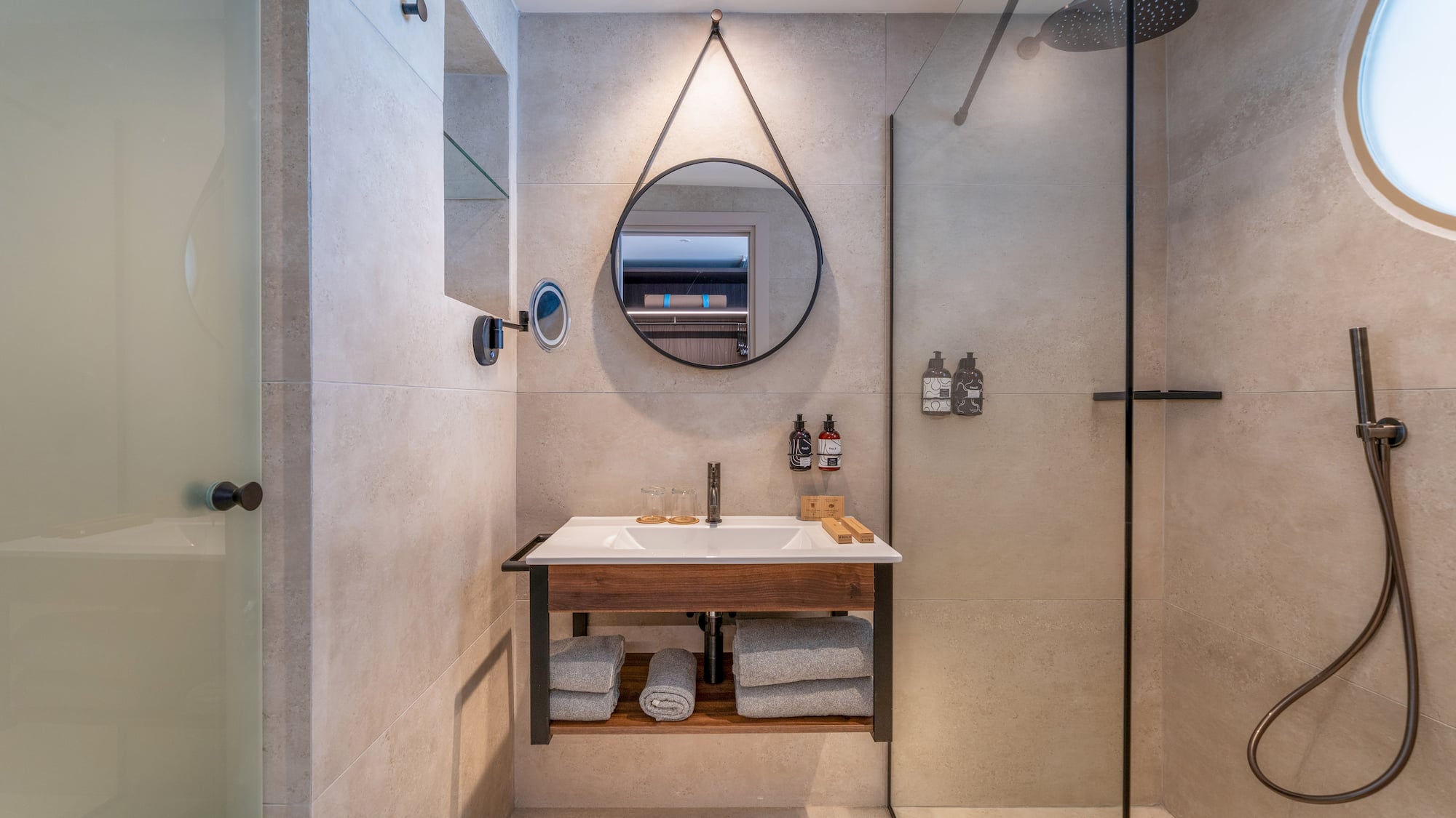 Modern bathroom with rain shower, floating vanity, and round mirror.