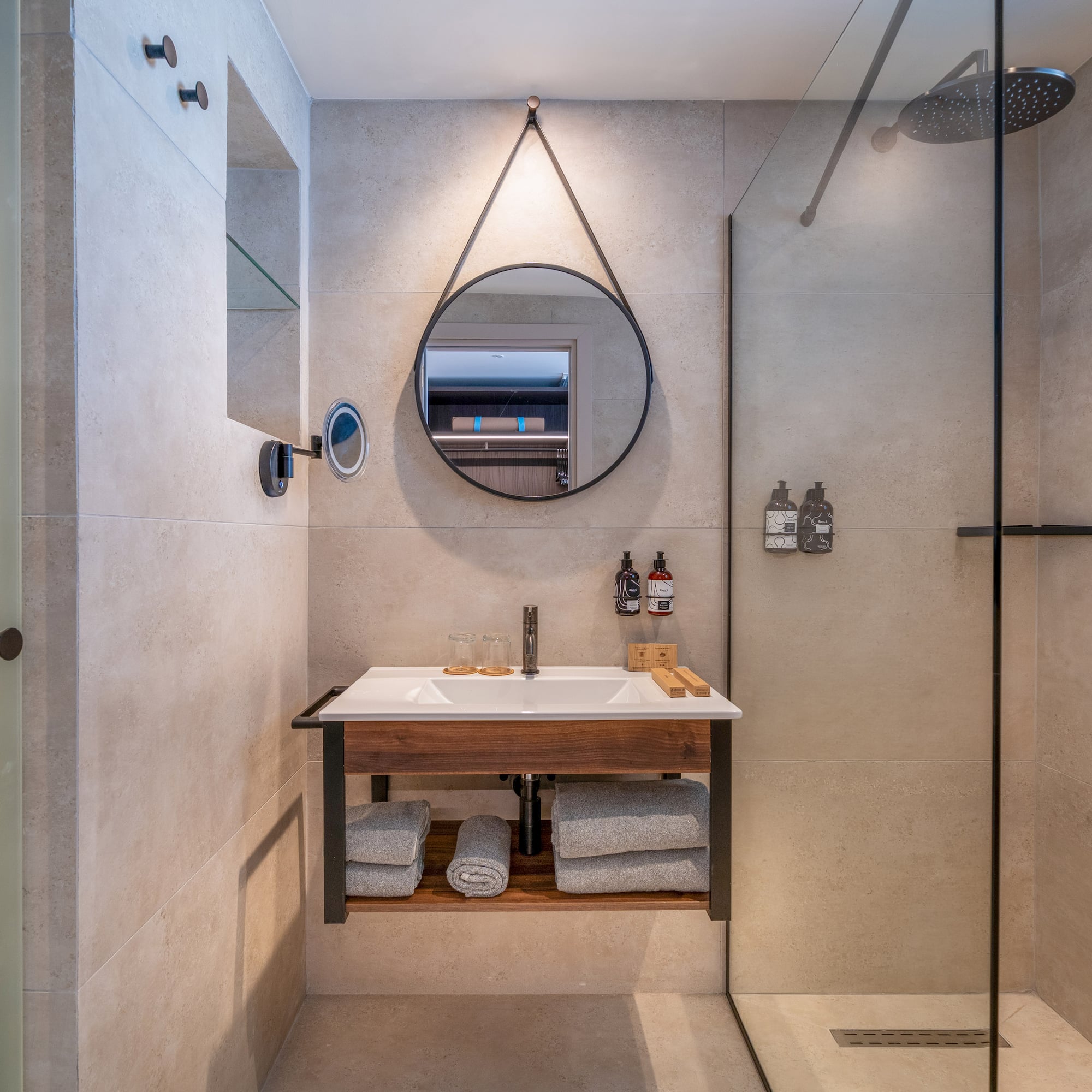 Modern bathroom with floating vanity, round mirror, and glass shower.
