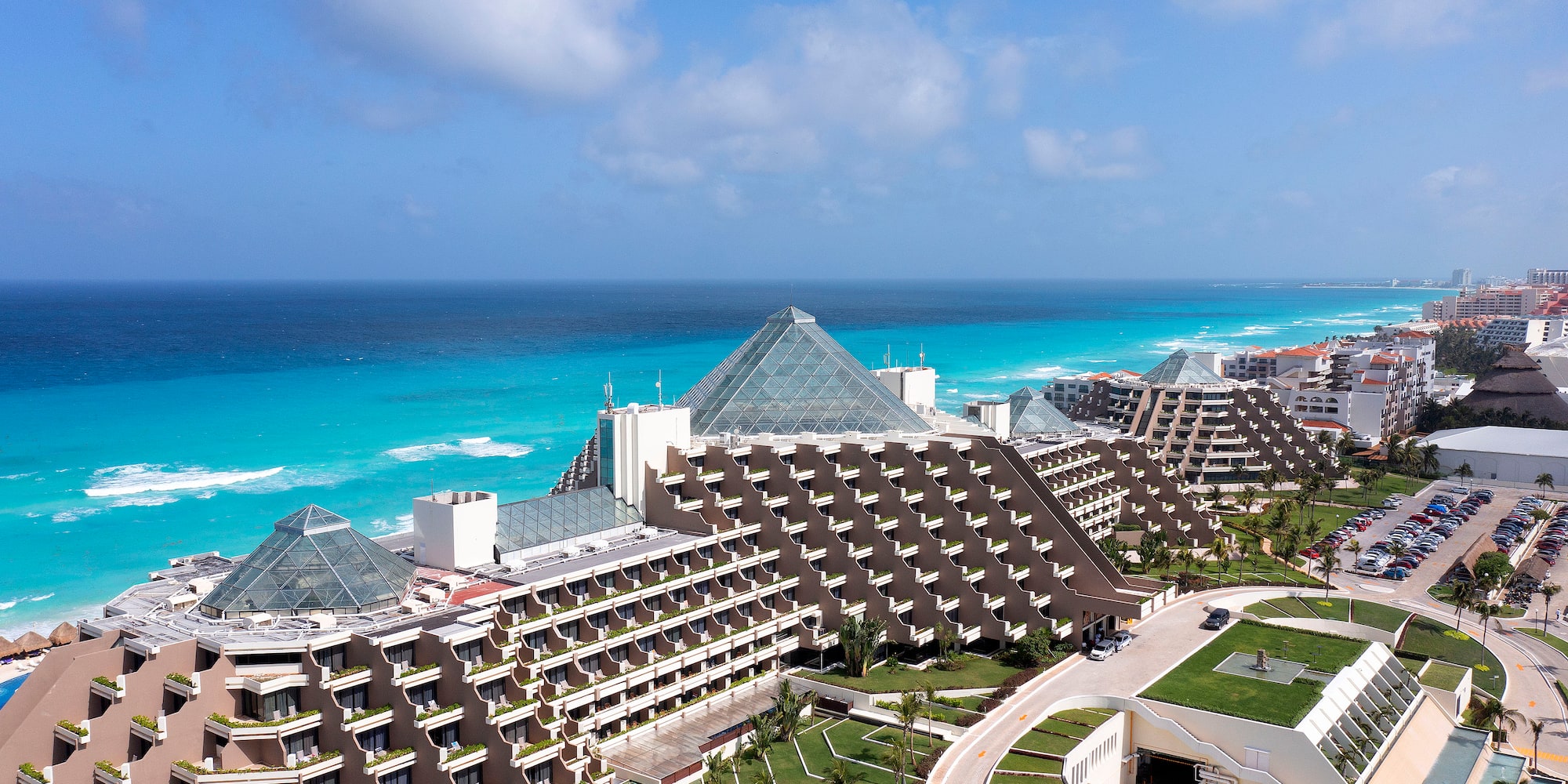 a large hotel with a beach and blue water