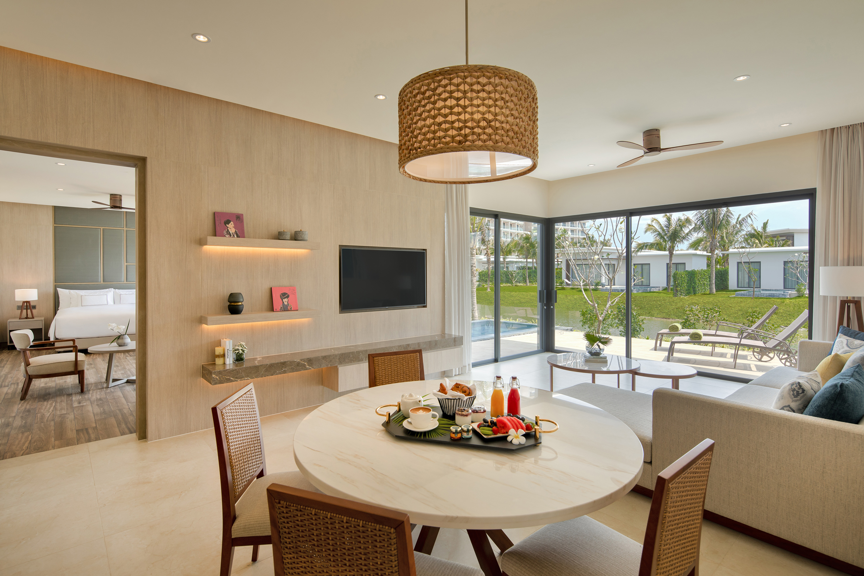 Modern luxury suite with breakfast on dining table, living area, pool view.