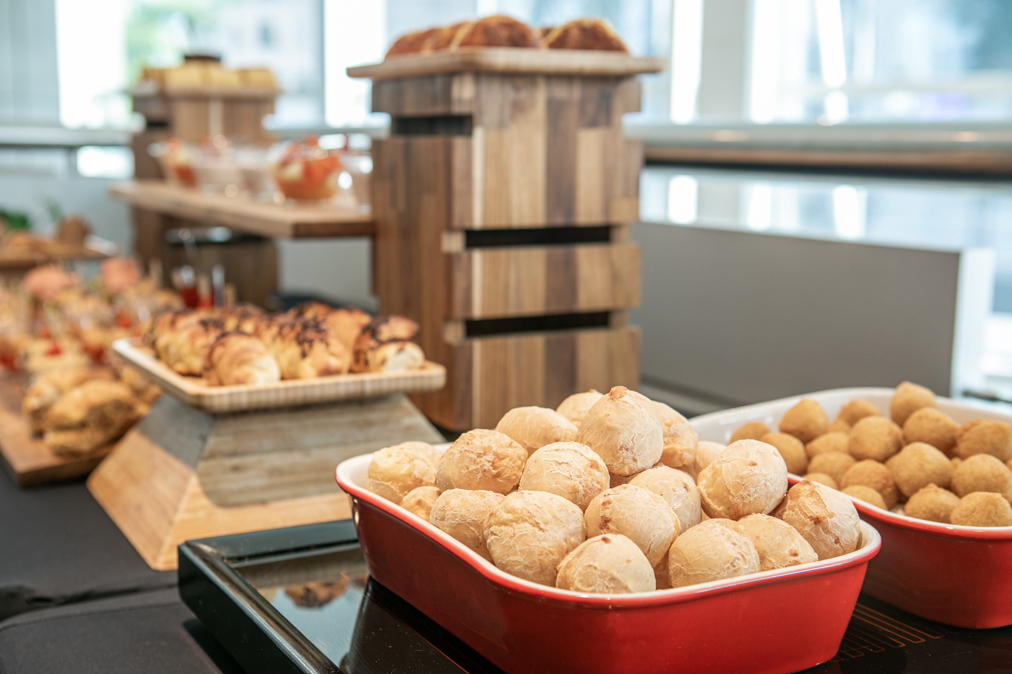 Brazilian Pão de Queijo and croissants on a breakfast buffet display.