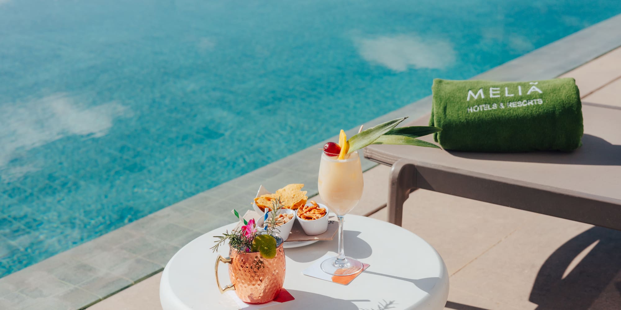 Meliá resort poolside cocktails and snacks by a blue swimming pool.