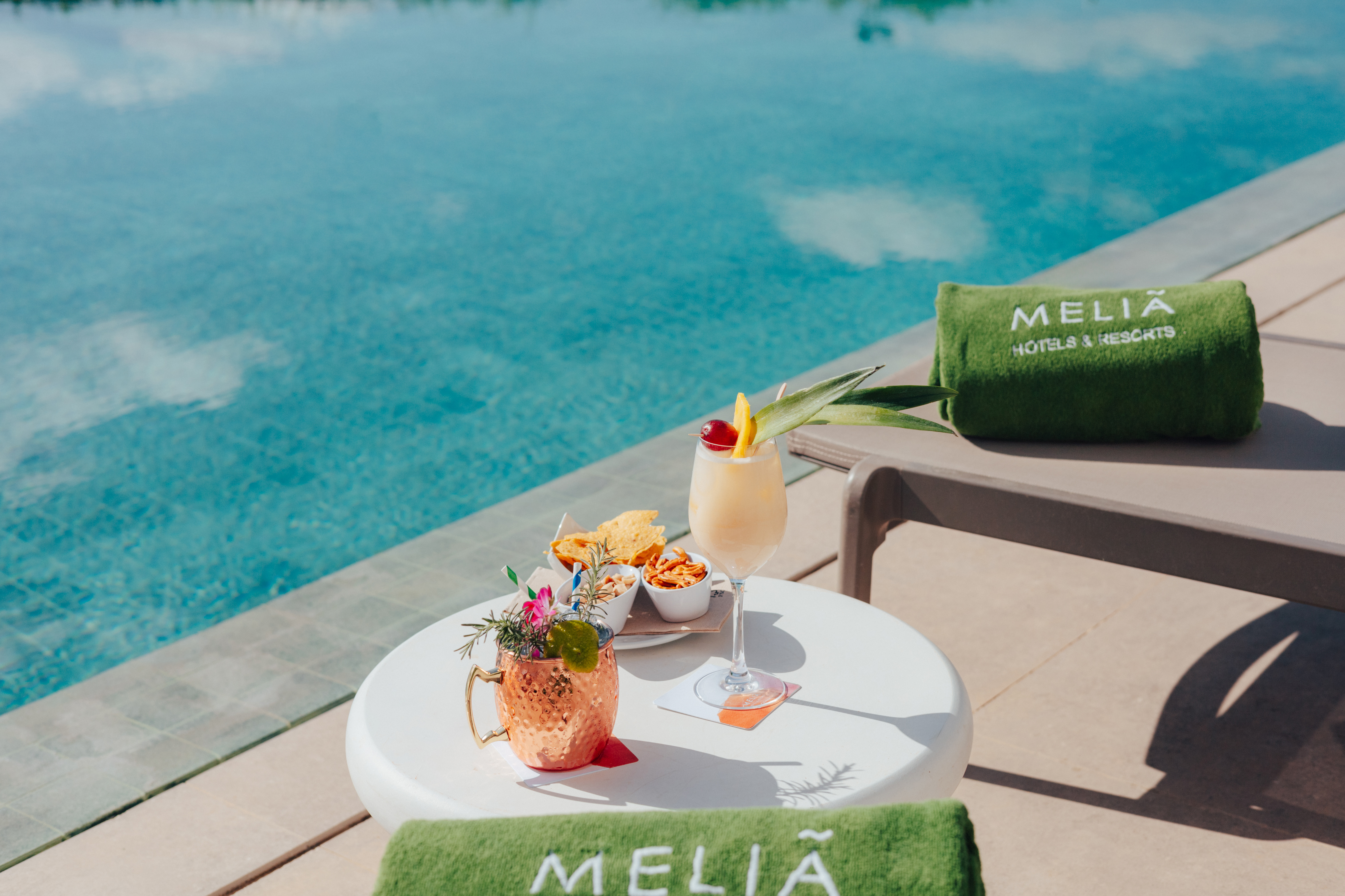 Meliá resort poolside cocktails and snacks by a blue swimming pool.