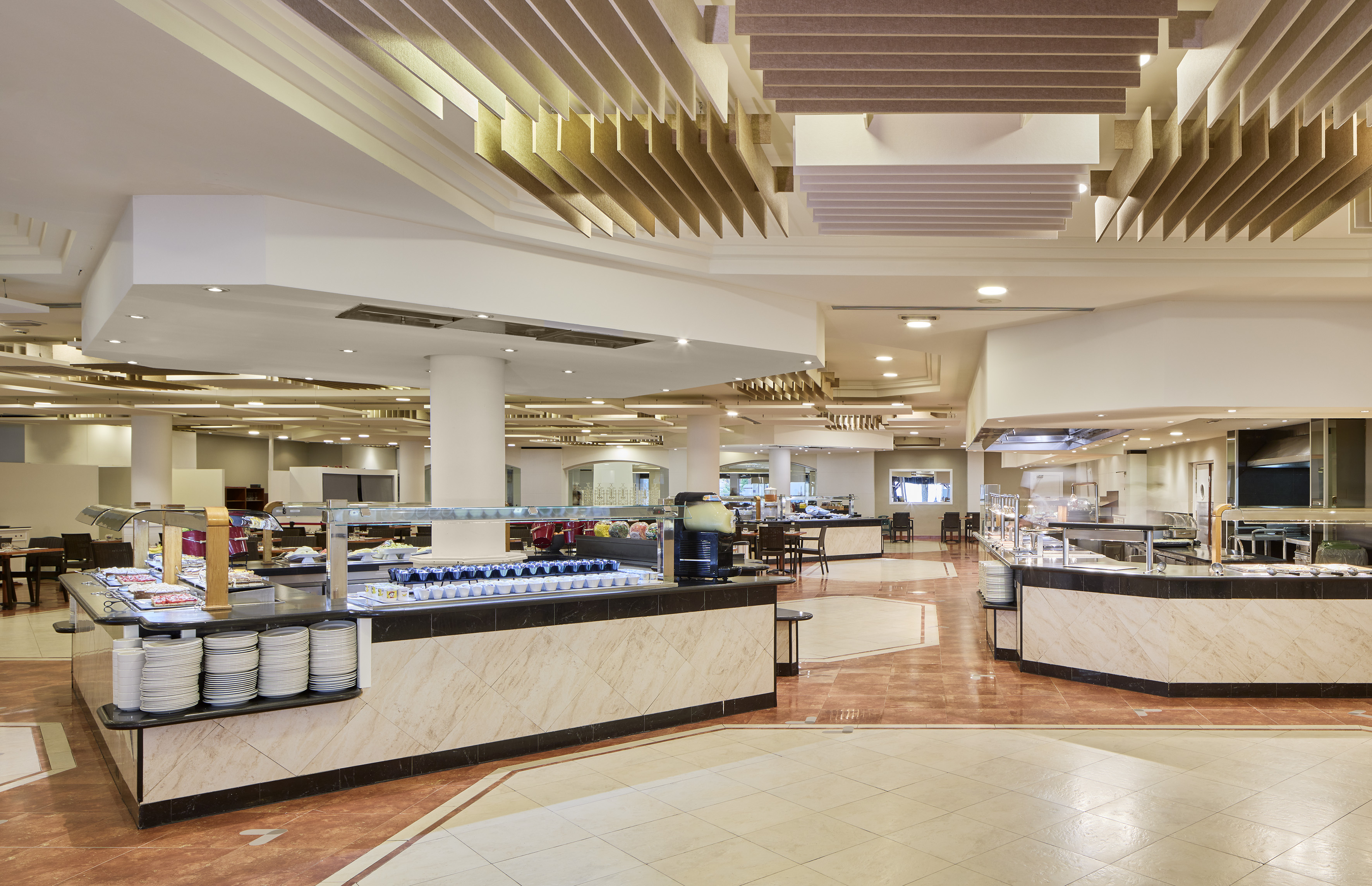 Hotel buffet dining hall with multiple food counters and modern interior design.