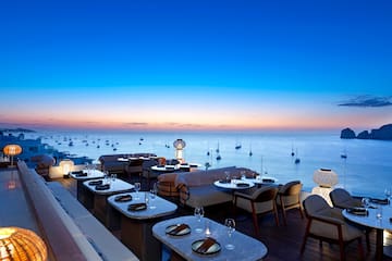 a restaurant with tables and chairs overlooking the ocean