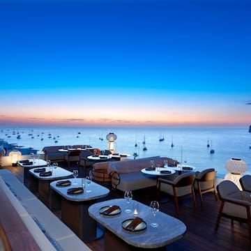 a restaurant with tables and chairs overlooking the ocean