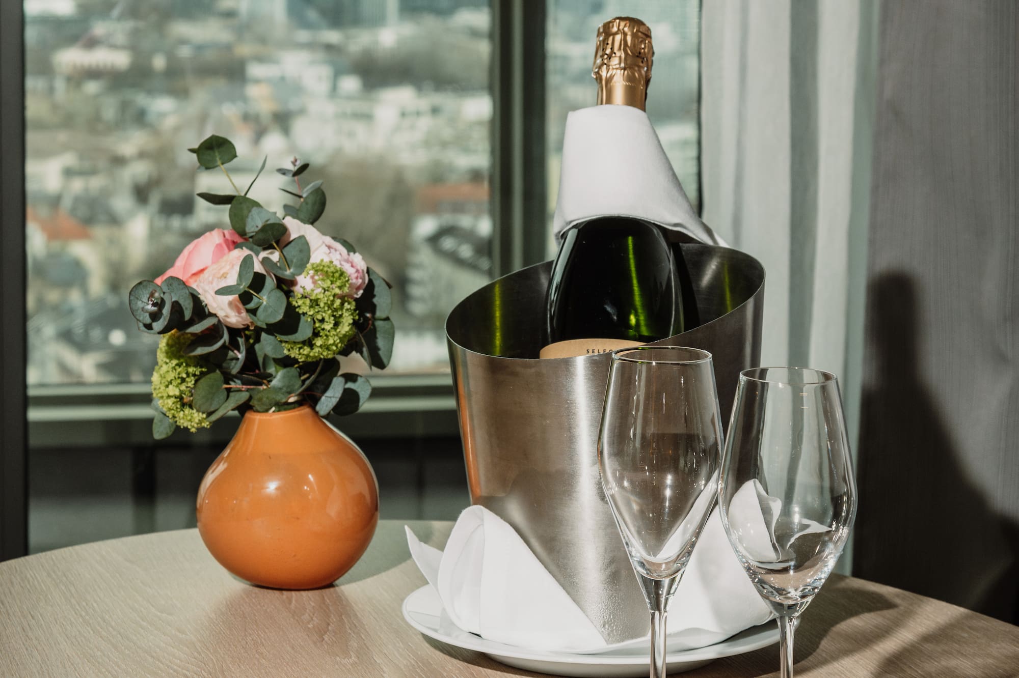 a bottle of champagne in a bucket next to a plate of fruit and a vase of flowers