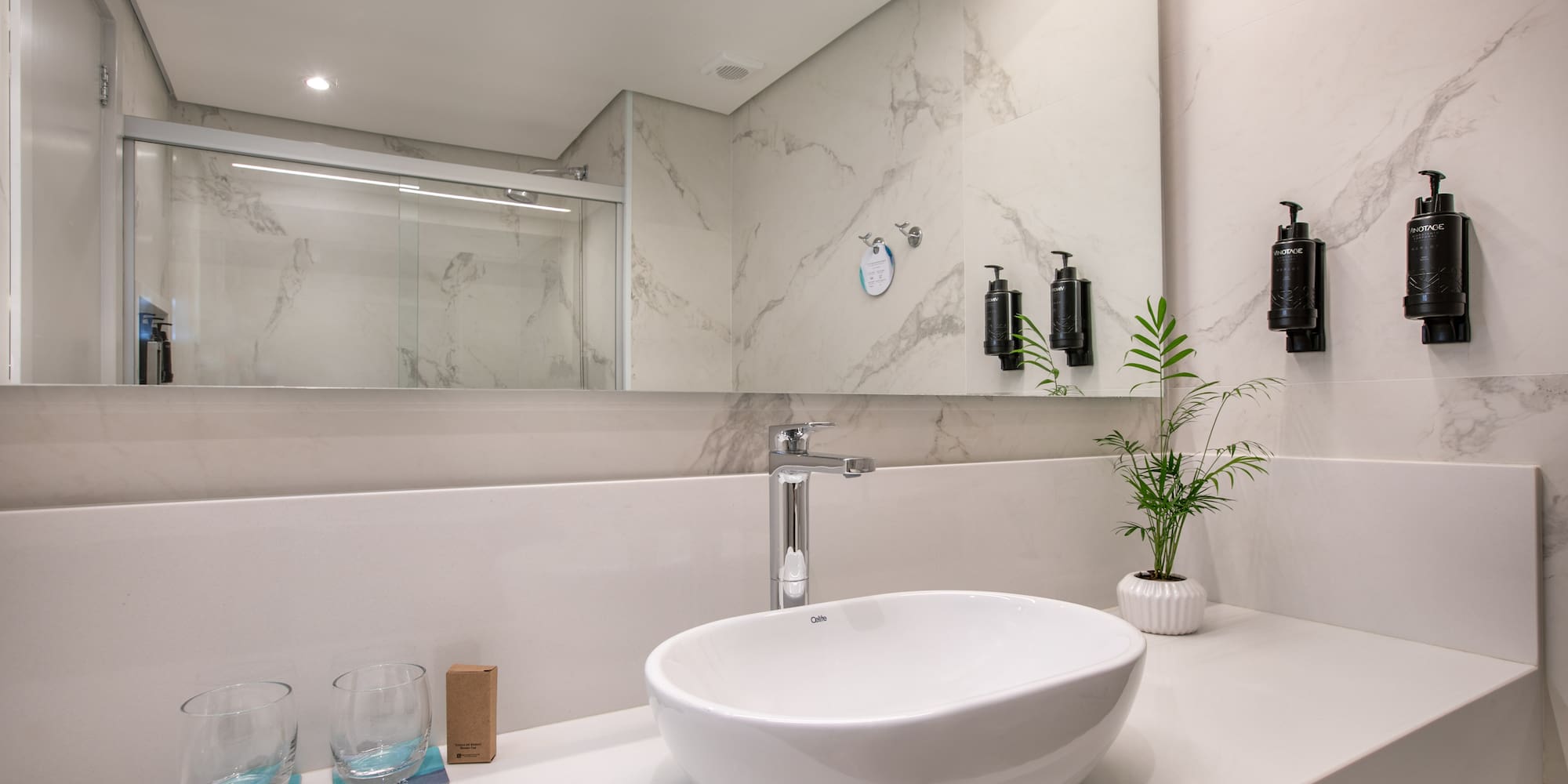 Modern bathroom vanity: white sink, chrome faucet, marble-look wall tiles.