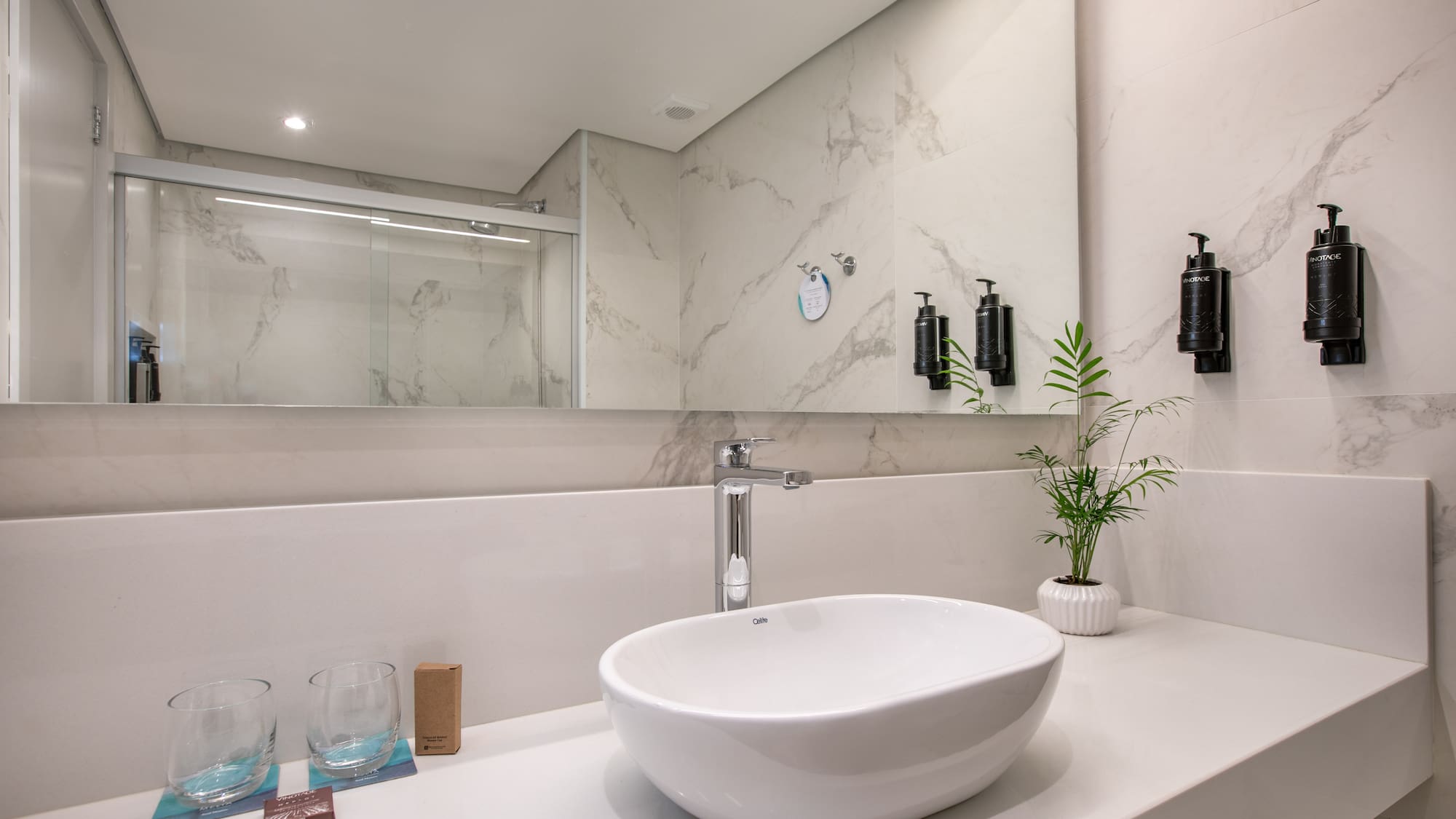 Modern bathroom vanity: white sink, chrome faucet, marble-look wall tiles.