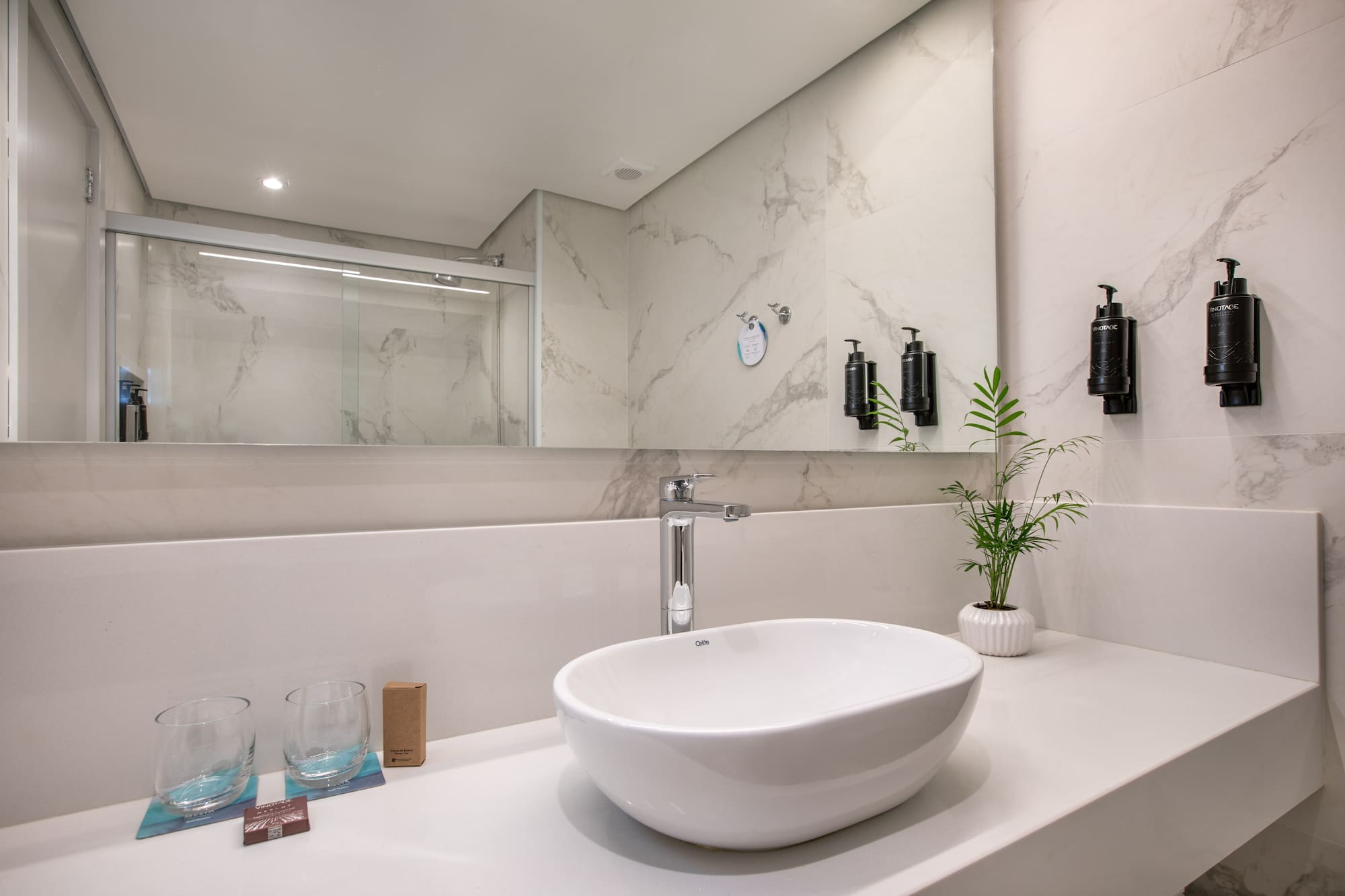 Modern bathroom vanity: white sink, chrome faucet, marble-look wall tiles.