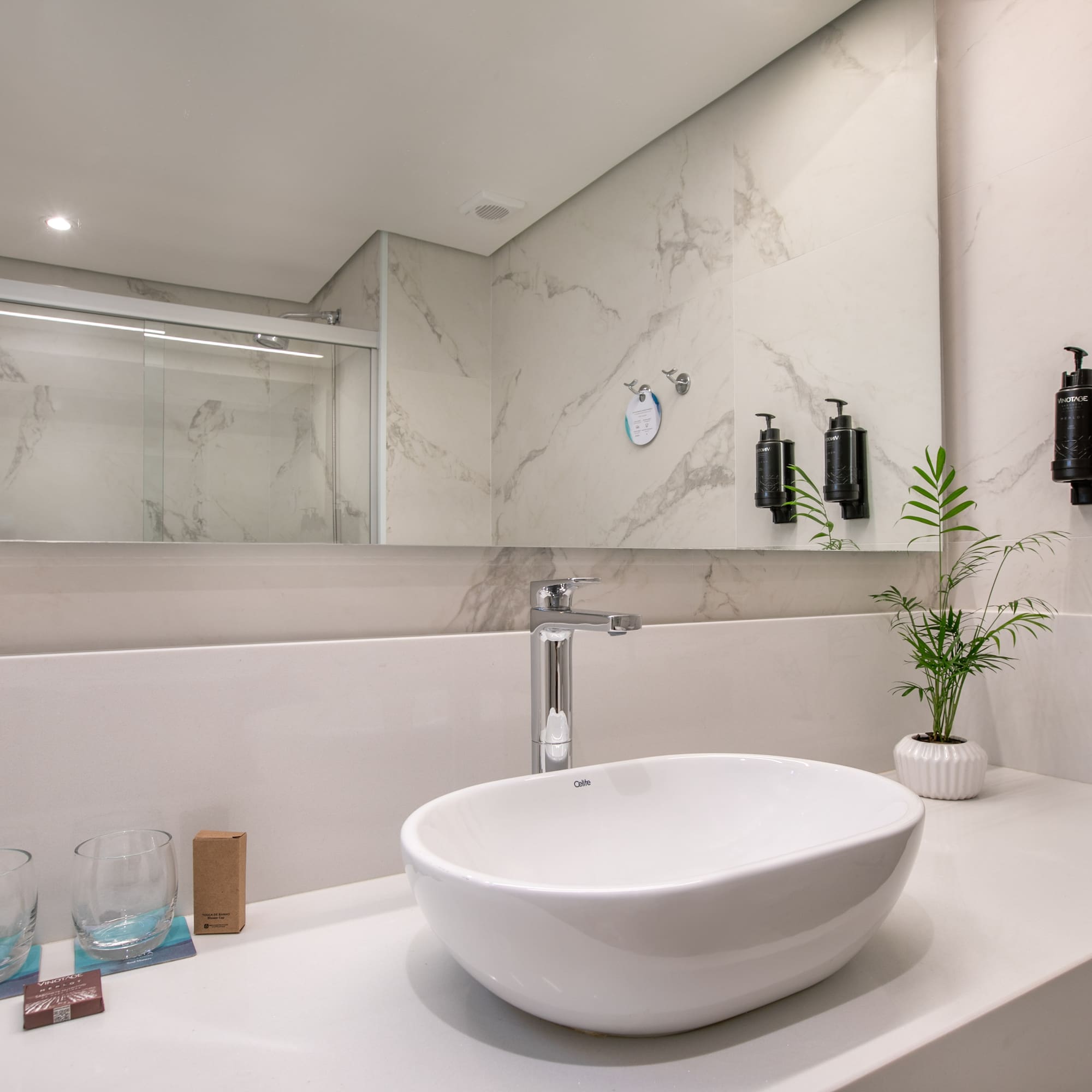 Modern bathroom vanity: white sink, chrome faucet, marble-look wall tiles.