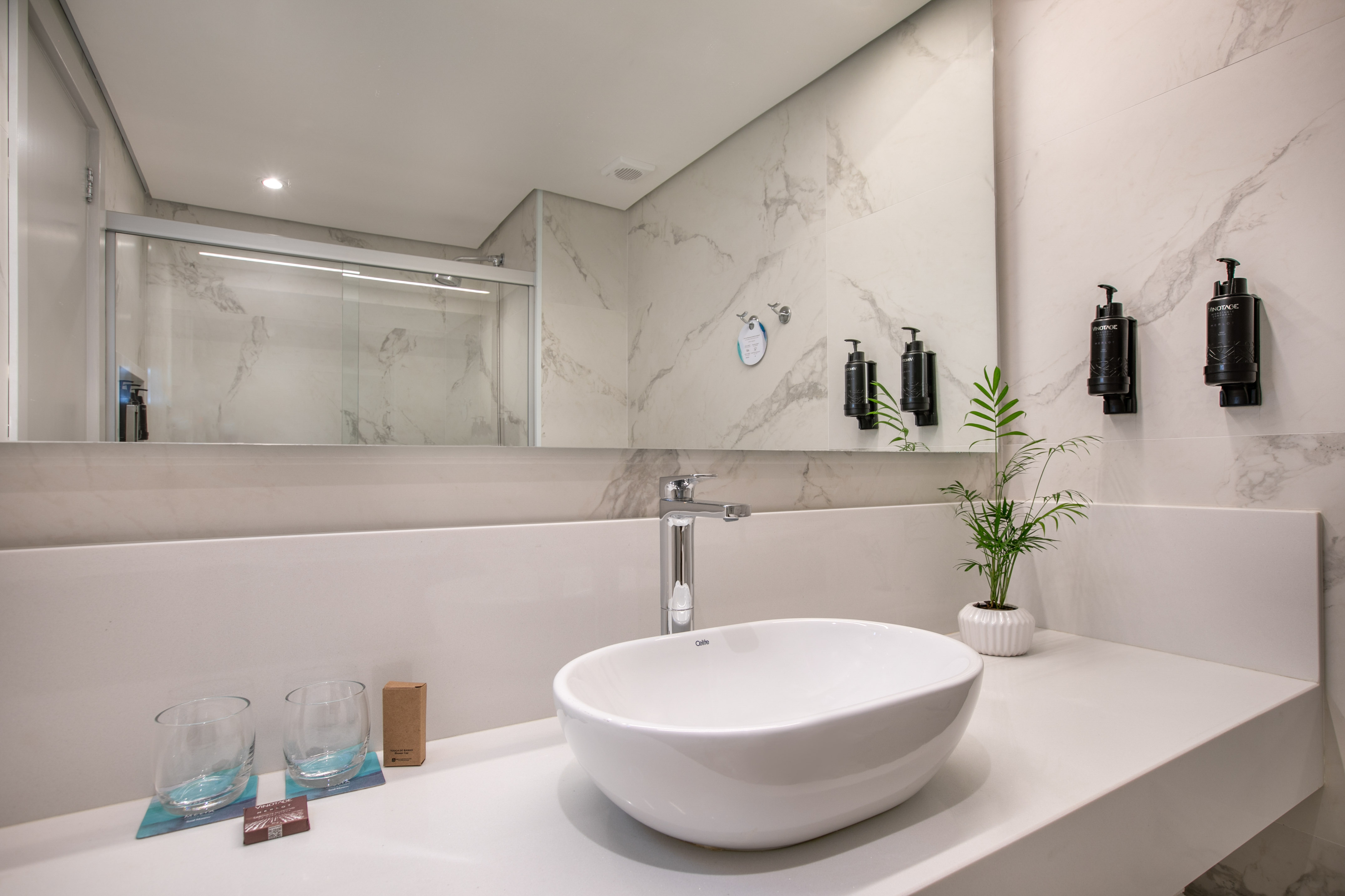 Modern bathroom vanity: white sink, chrome faucet, marble-look wall tiles.