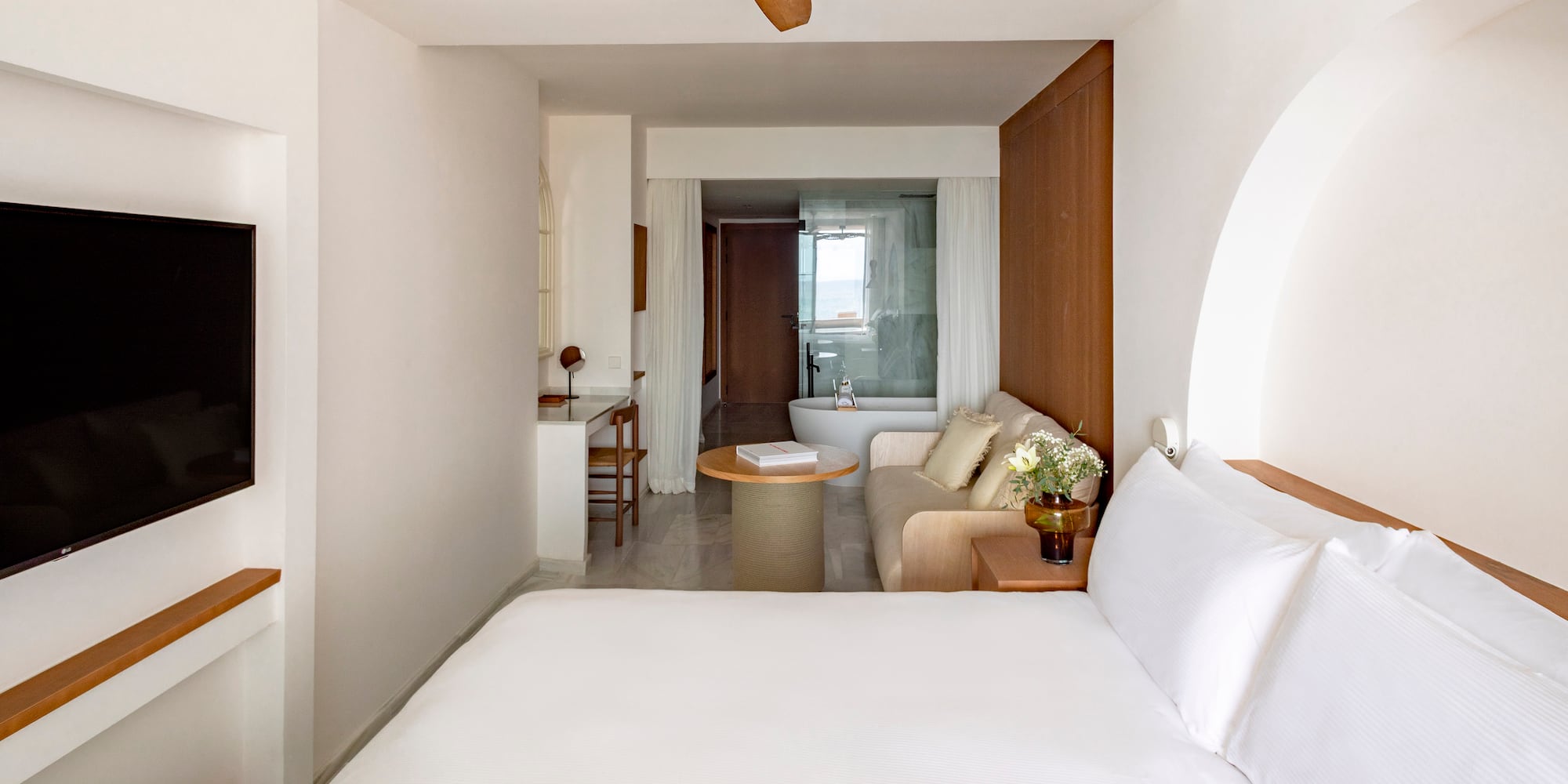 a room with a white bed and a white couch and a white bathtub