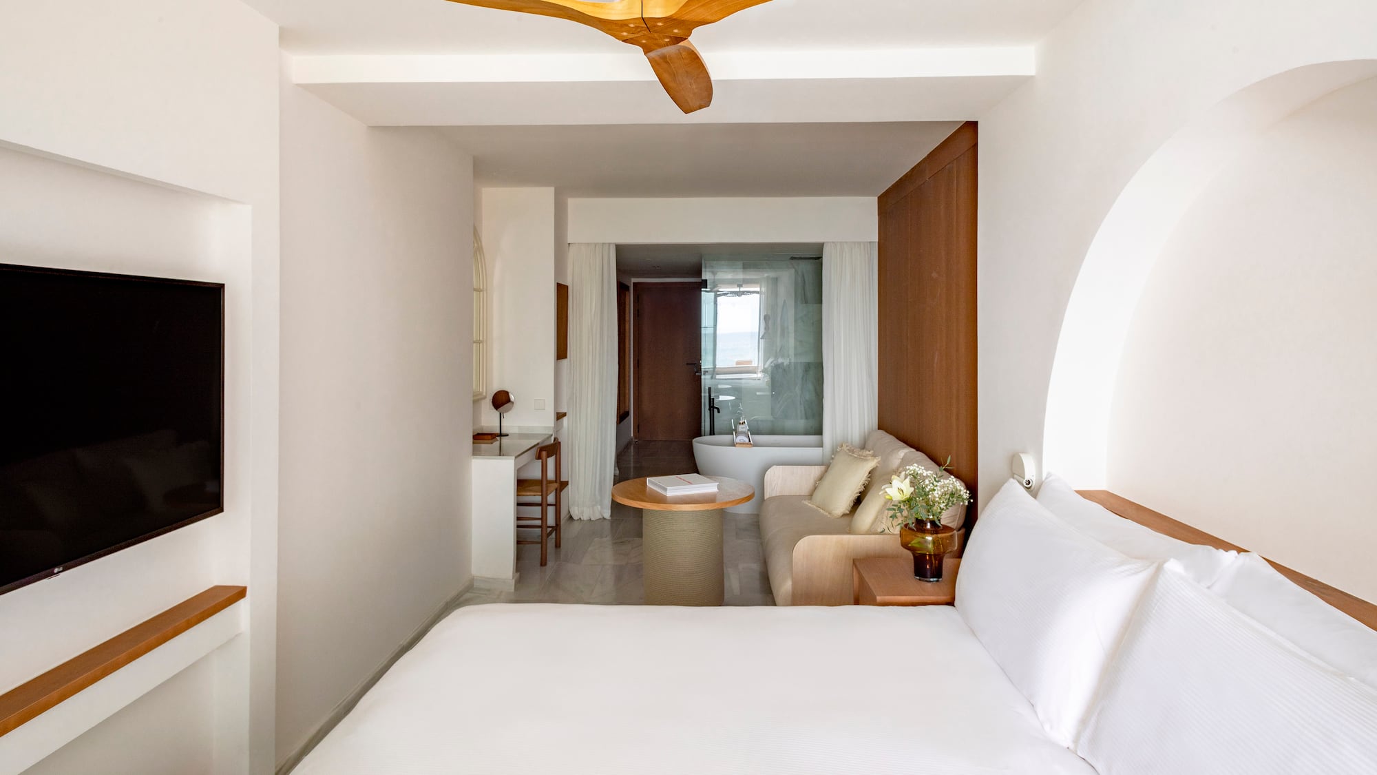 a room with a white bed and a white couch and a white bathtub