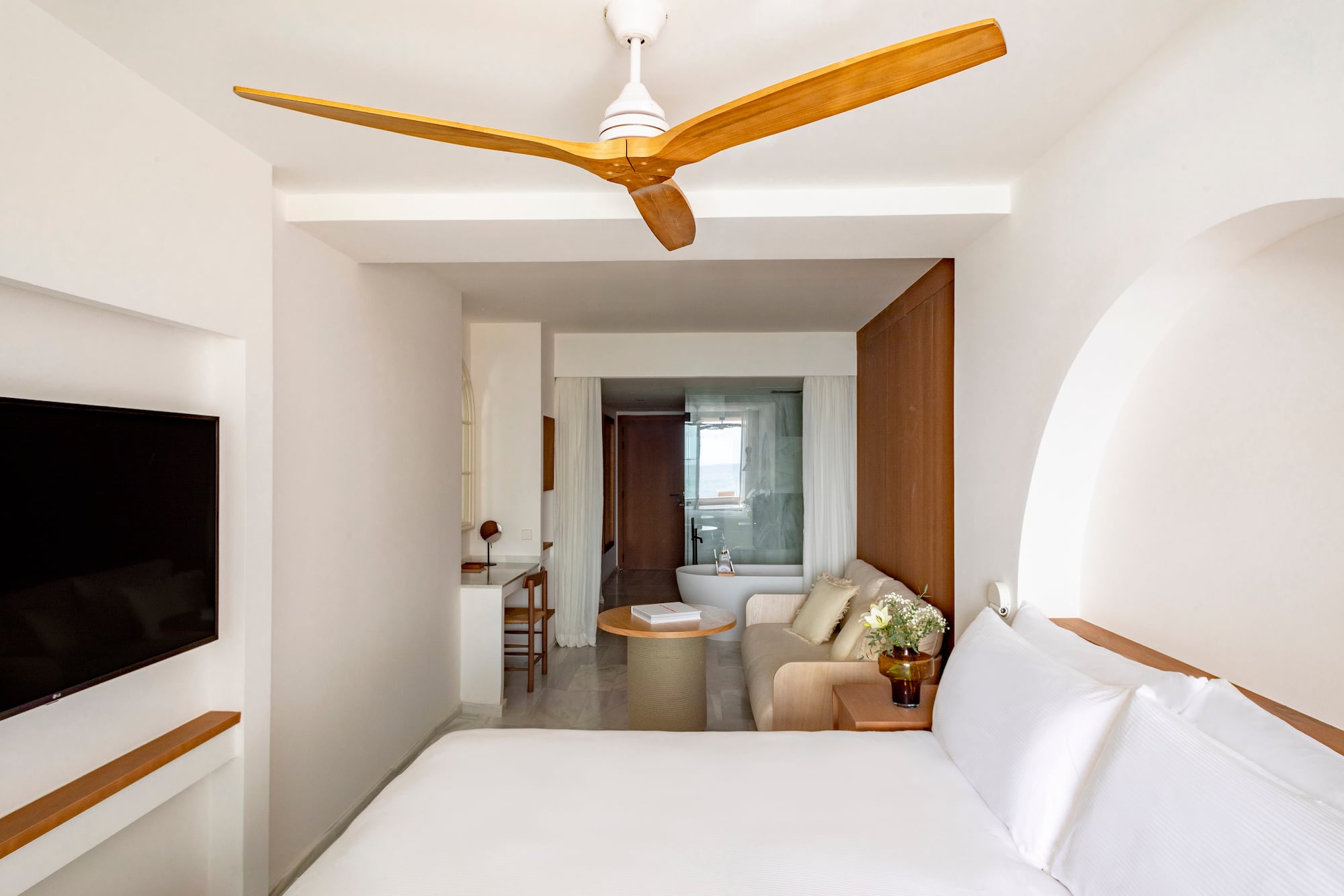 a room with a white bed and a white couch and a white bathtub