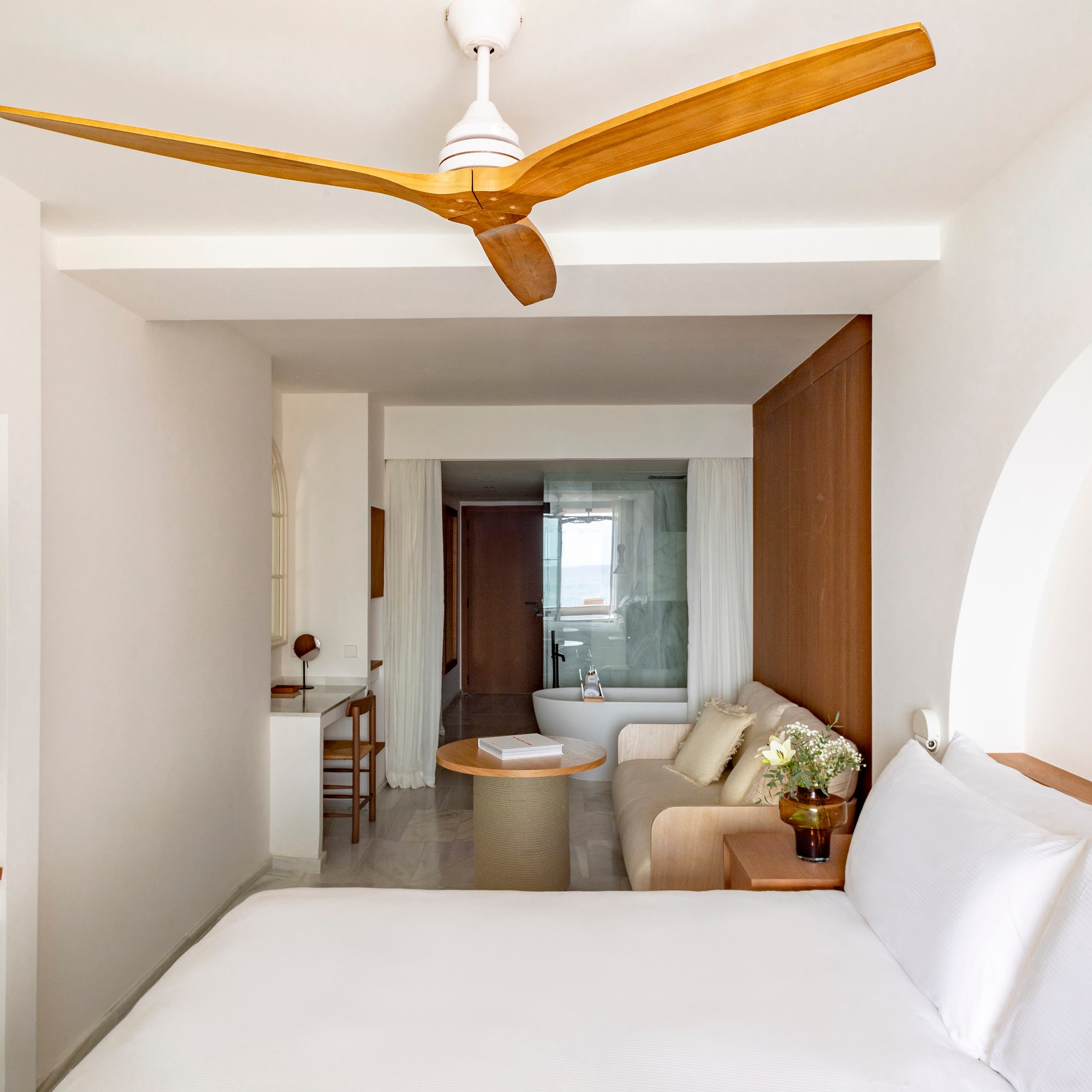 a room with a white bed and a white couch and a white bathtub