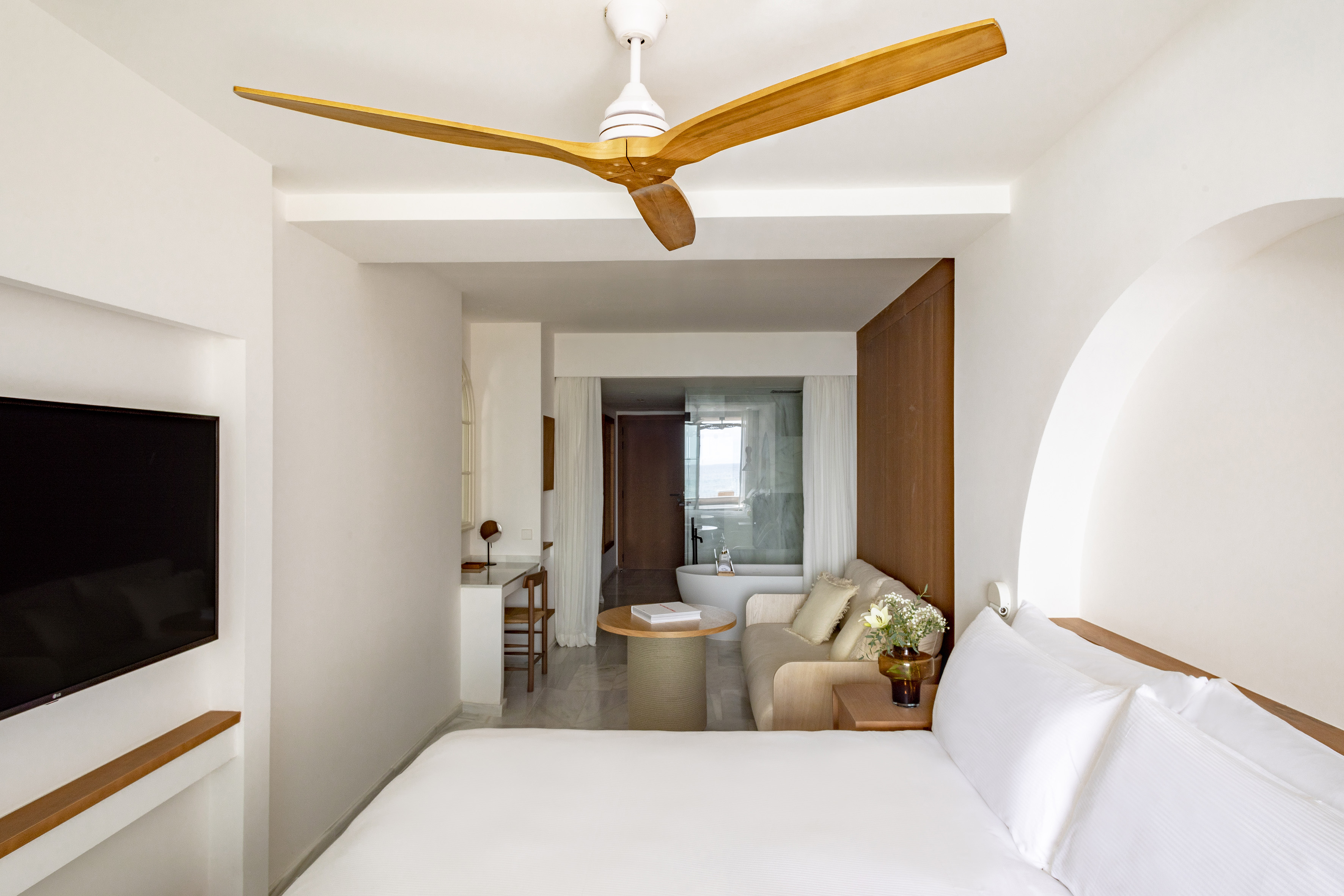 Modern luxury hotel suite with bed, living area, and bathroom sea view.
