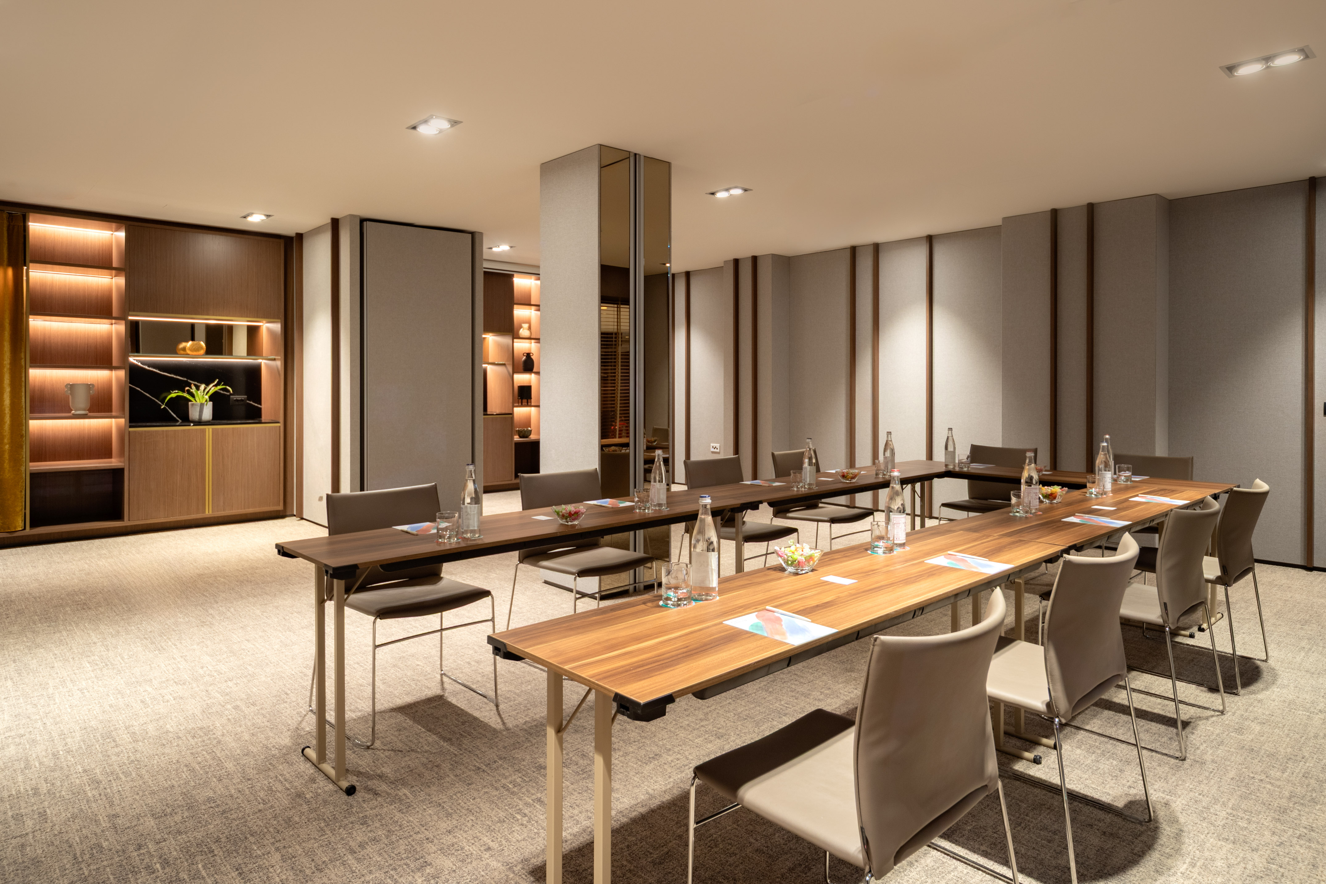 Modern meeting room setup with tables, chairs, water, and illuminated decor.