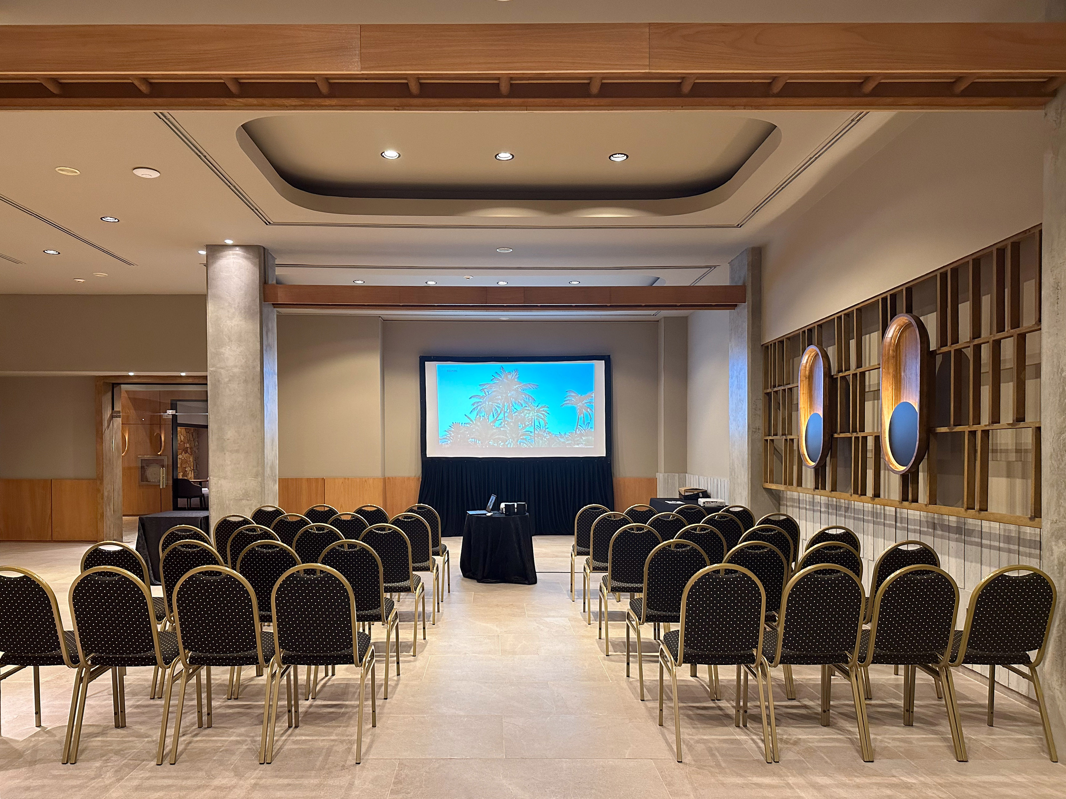 Modern empty meeting room setup for a presentation with screen and chairs.