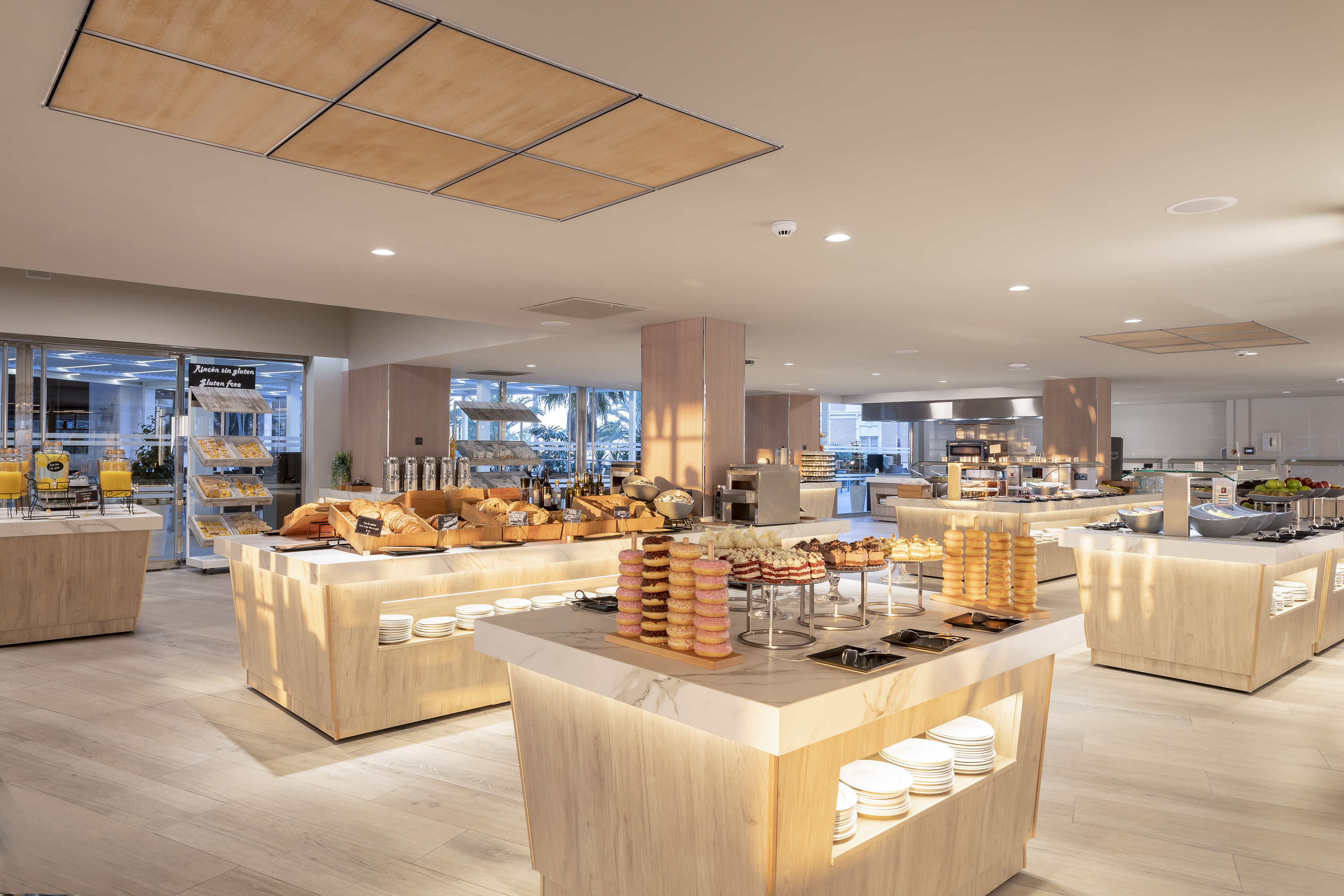 Modern hotel breakfast buffet with pastries, breads, donuts, and a gluten-free section.