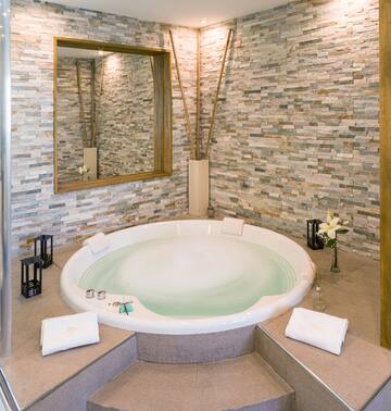 a large round tub in a room with a stone wall