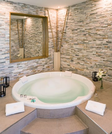 a large round tub in a room with a stone wall