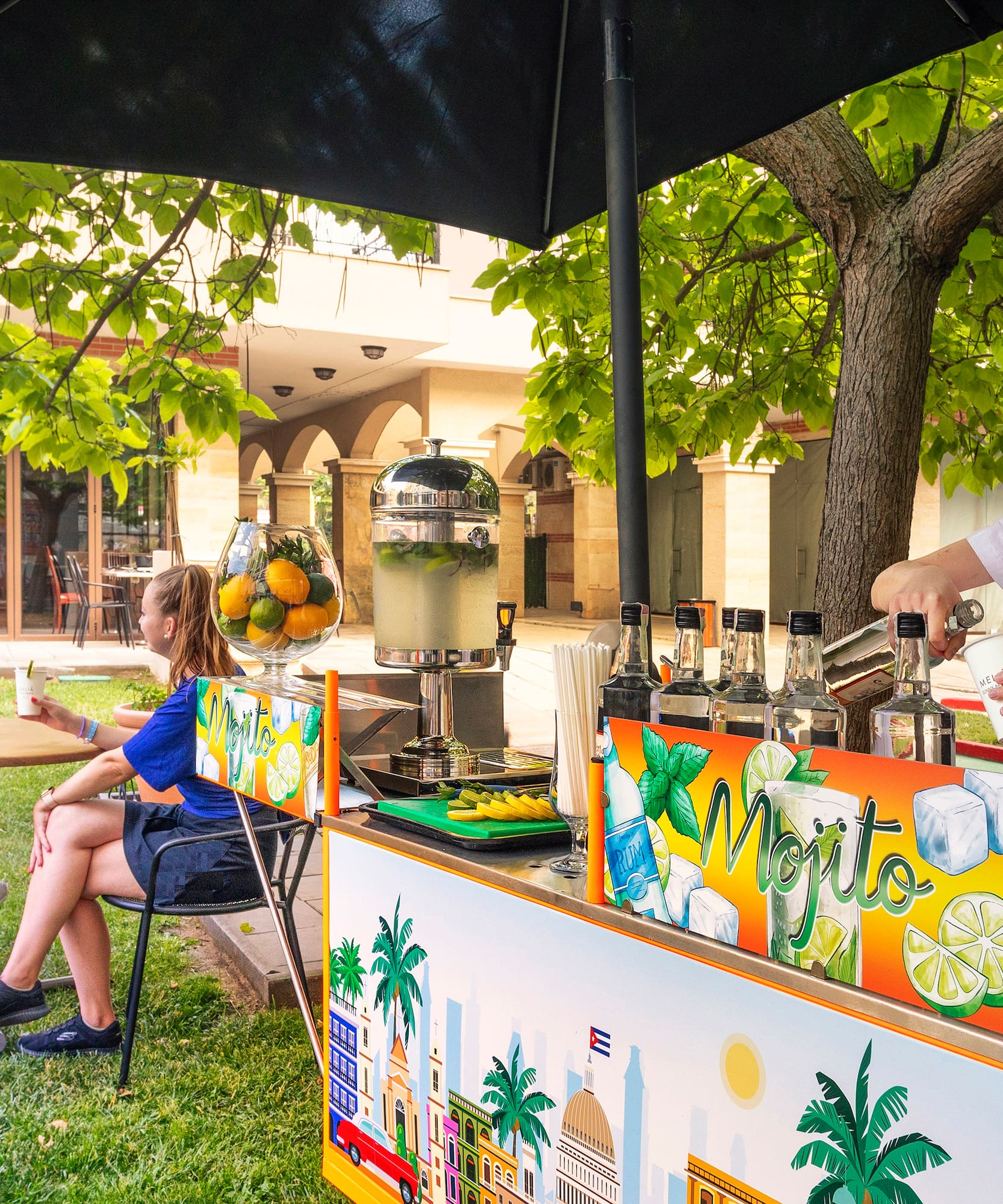 a woman standing behind a table with a drink stand