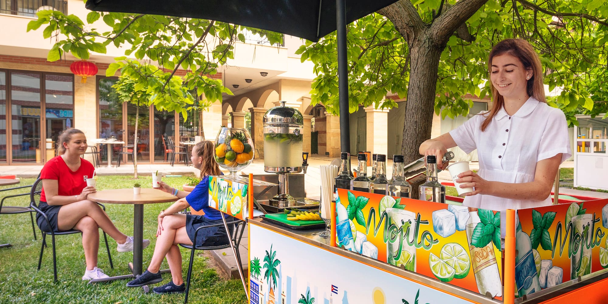 a woman standing behind a table with a drink stand
