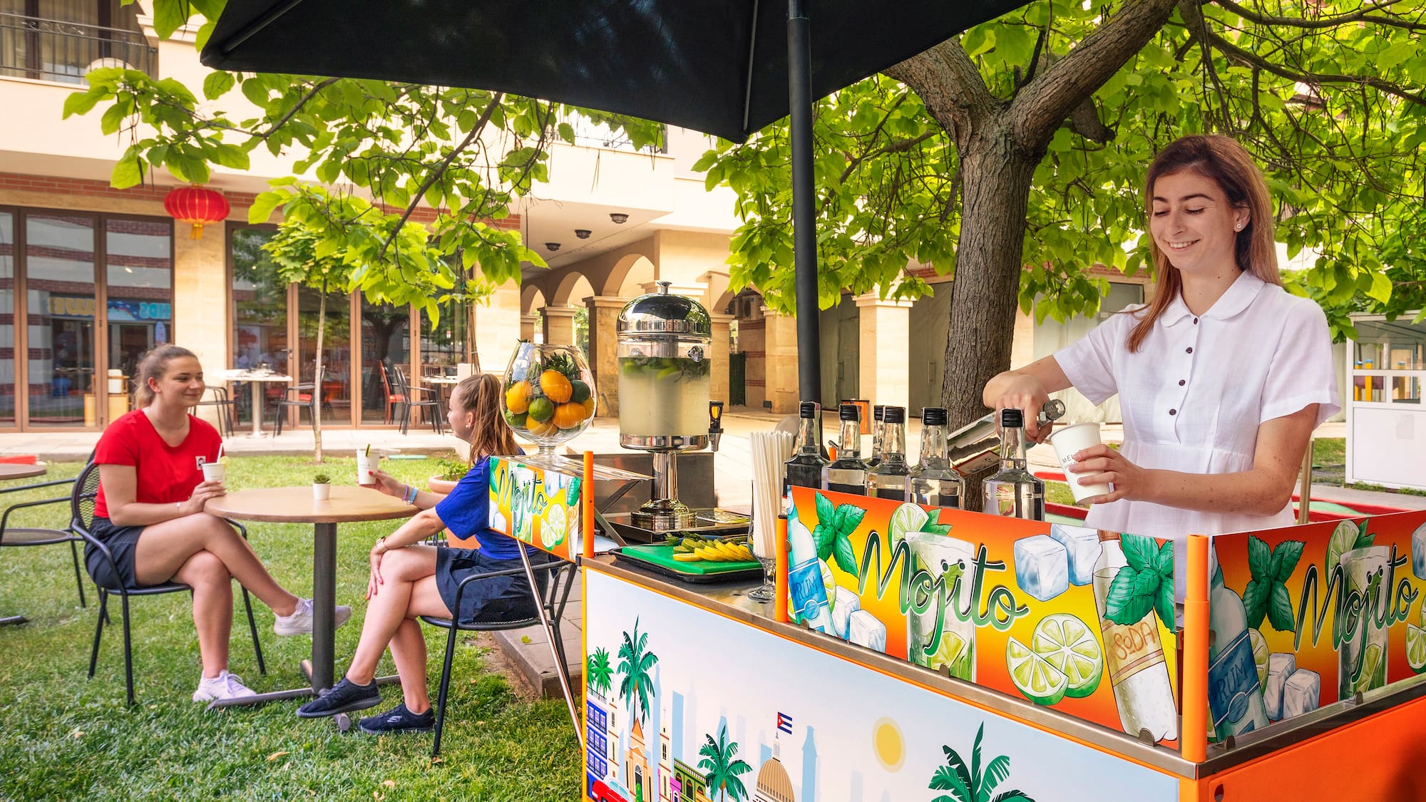 a woman standing behind a table with a drink stand