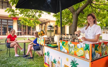 a woman standing behind a table with a drink stand