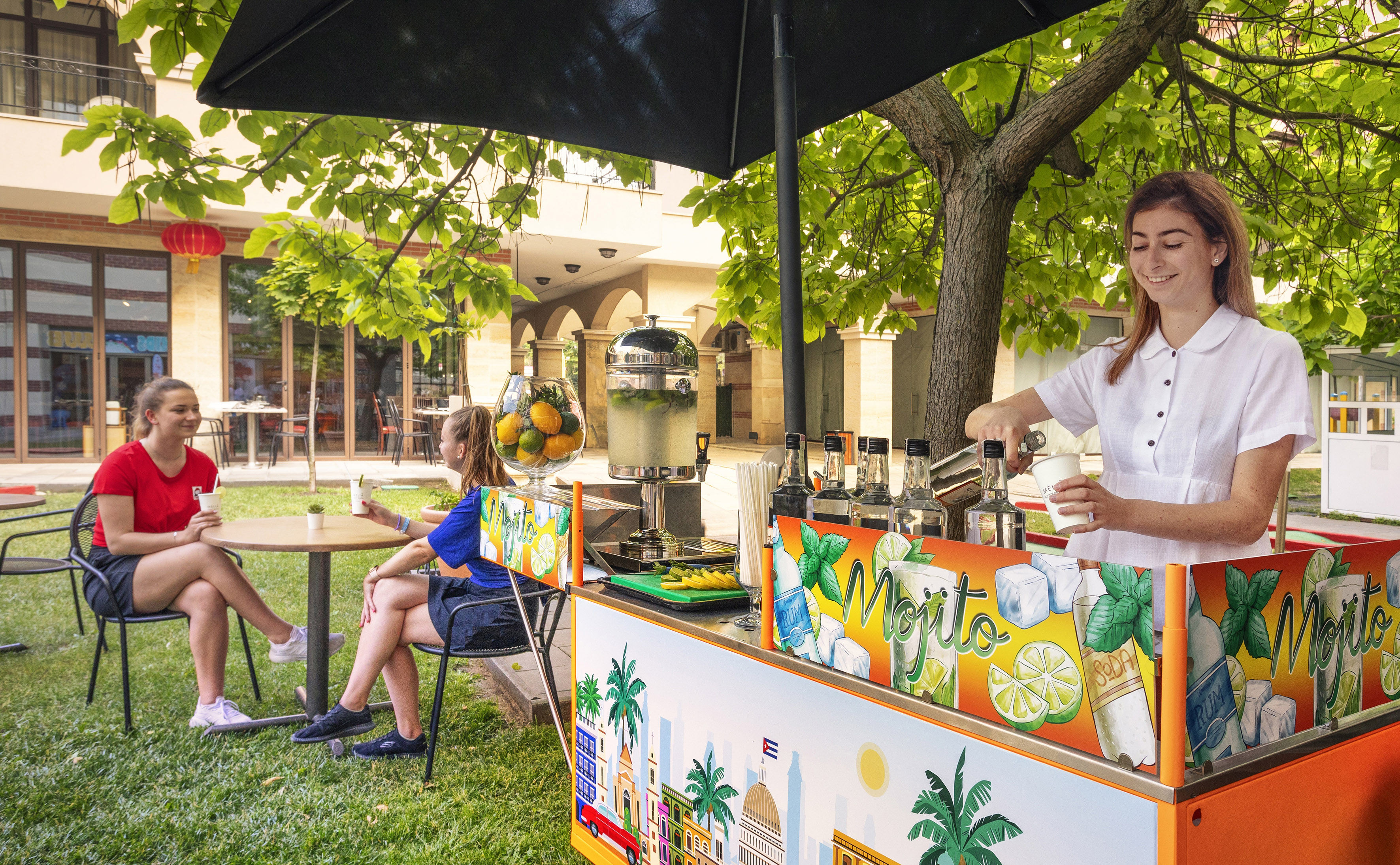 a woman standing behind a table with a drink stand