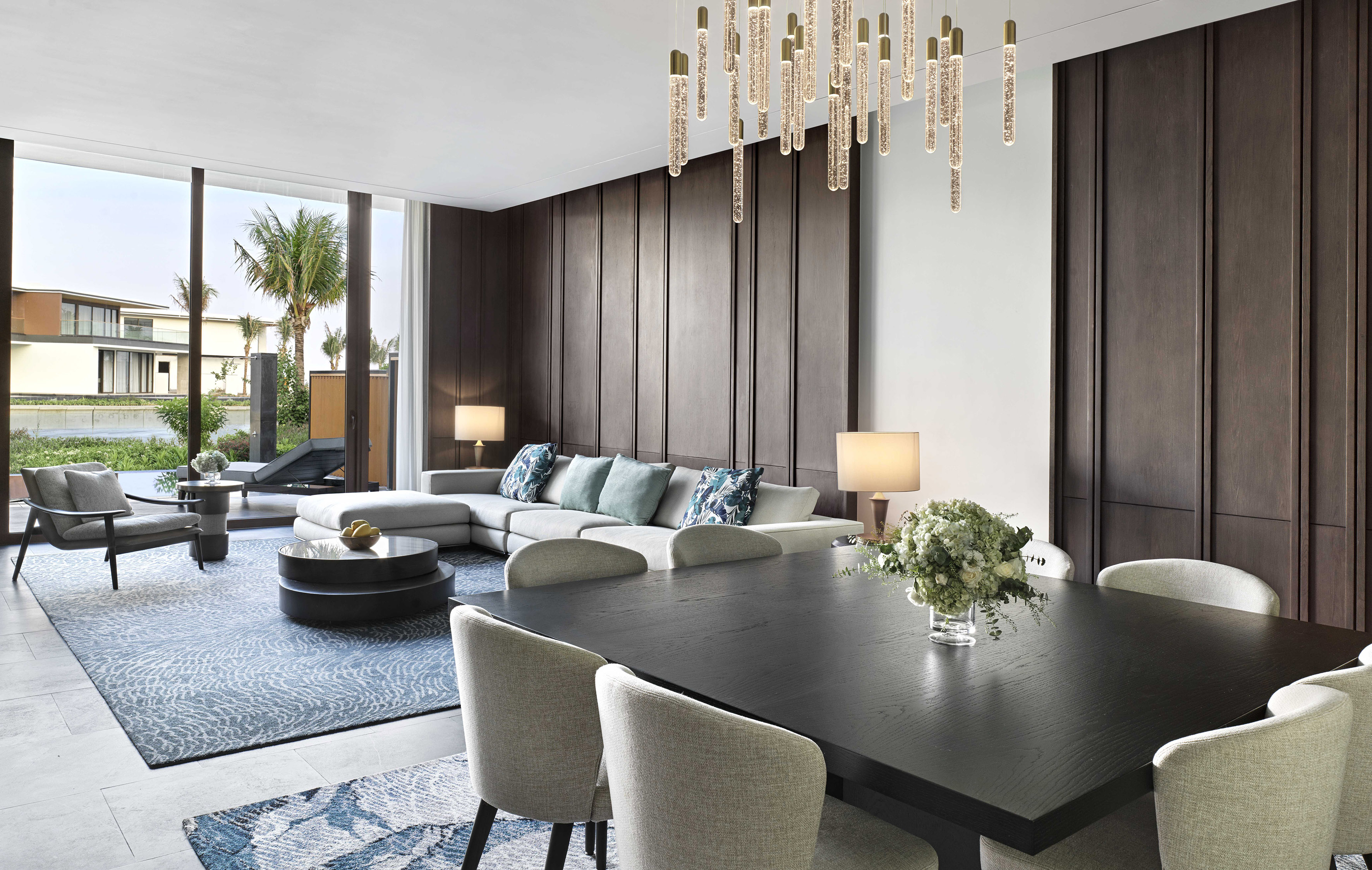 Chic living & dining room with contemporary chandelier and tropical view.
