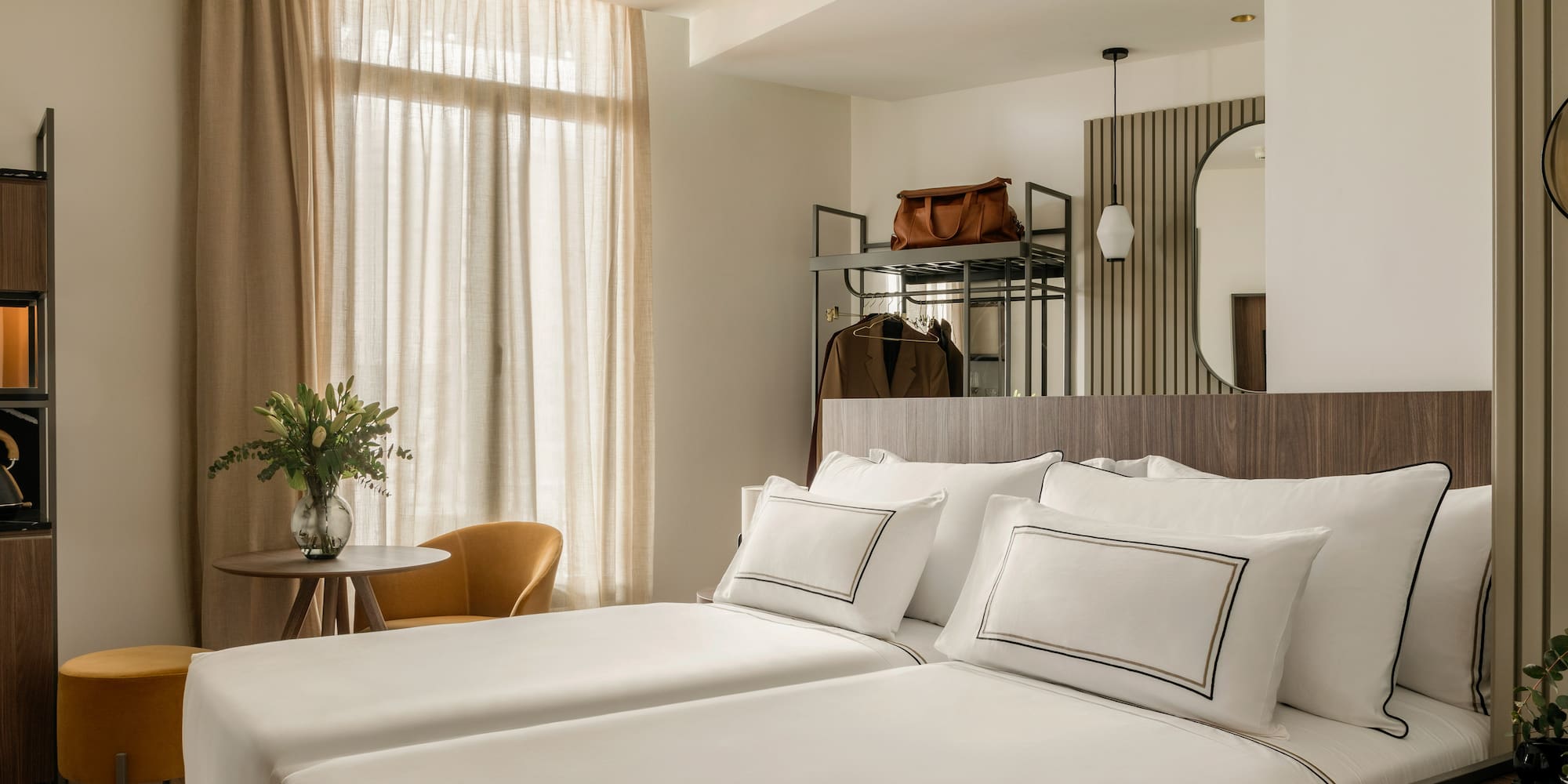 a room with white bedding and a mirror