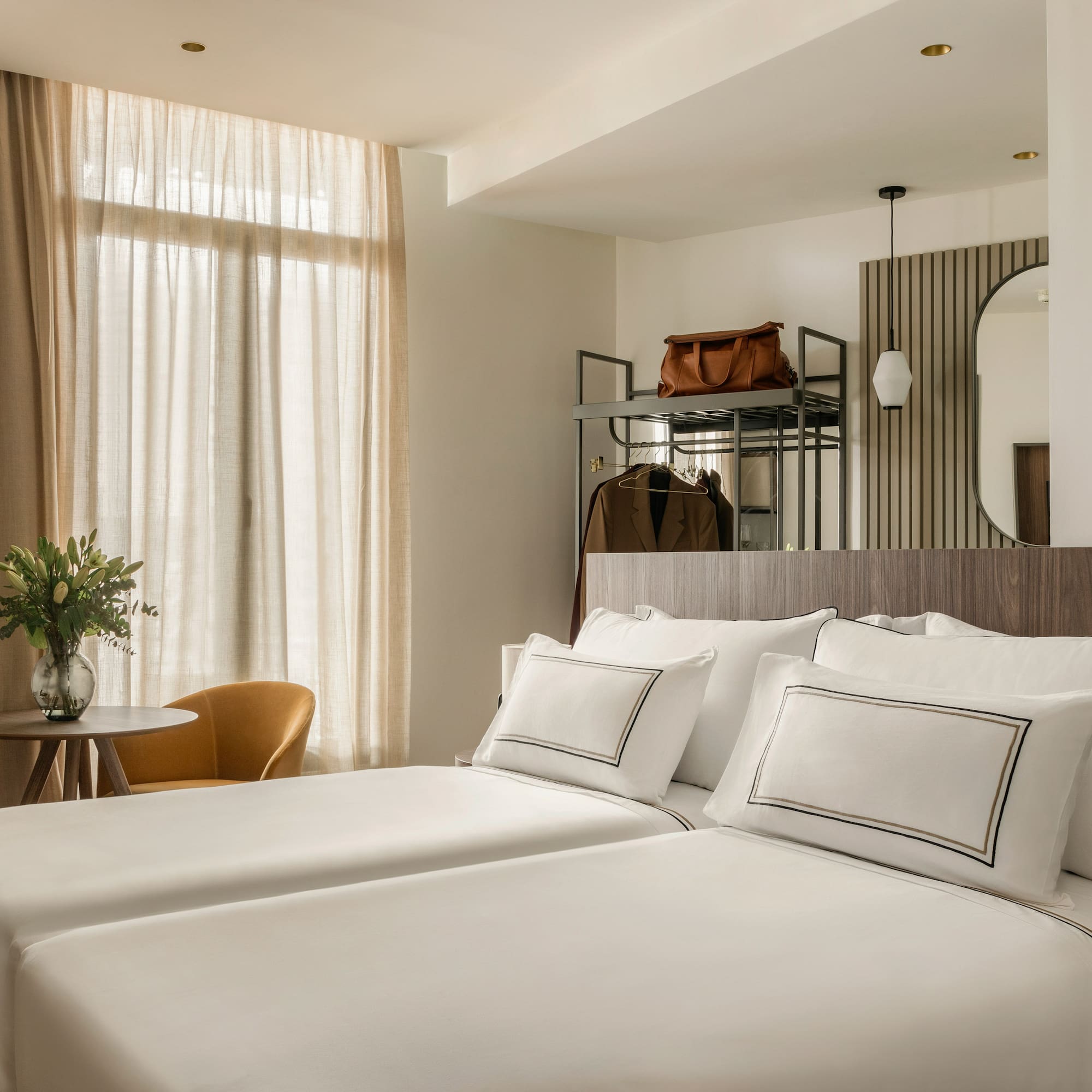 a room with white bedding and a mirror