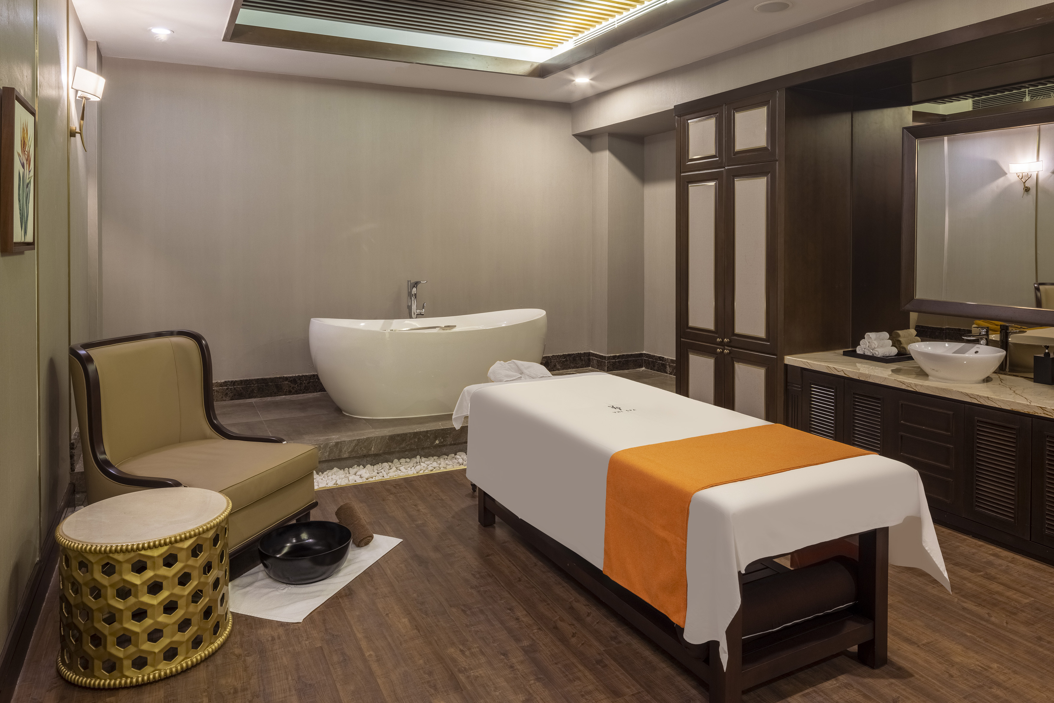 Luxury spa treatment room with massage table, bathtub, and vanity.