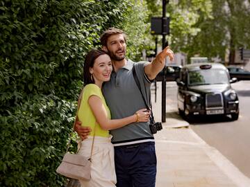 a man and woman standing on a sidewalk and pointing