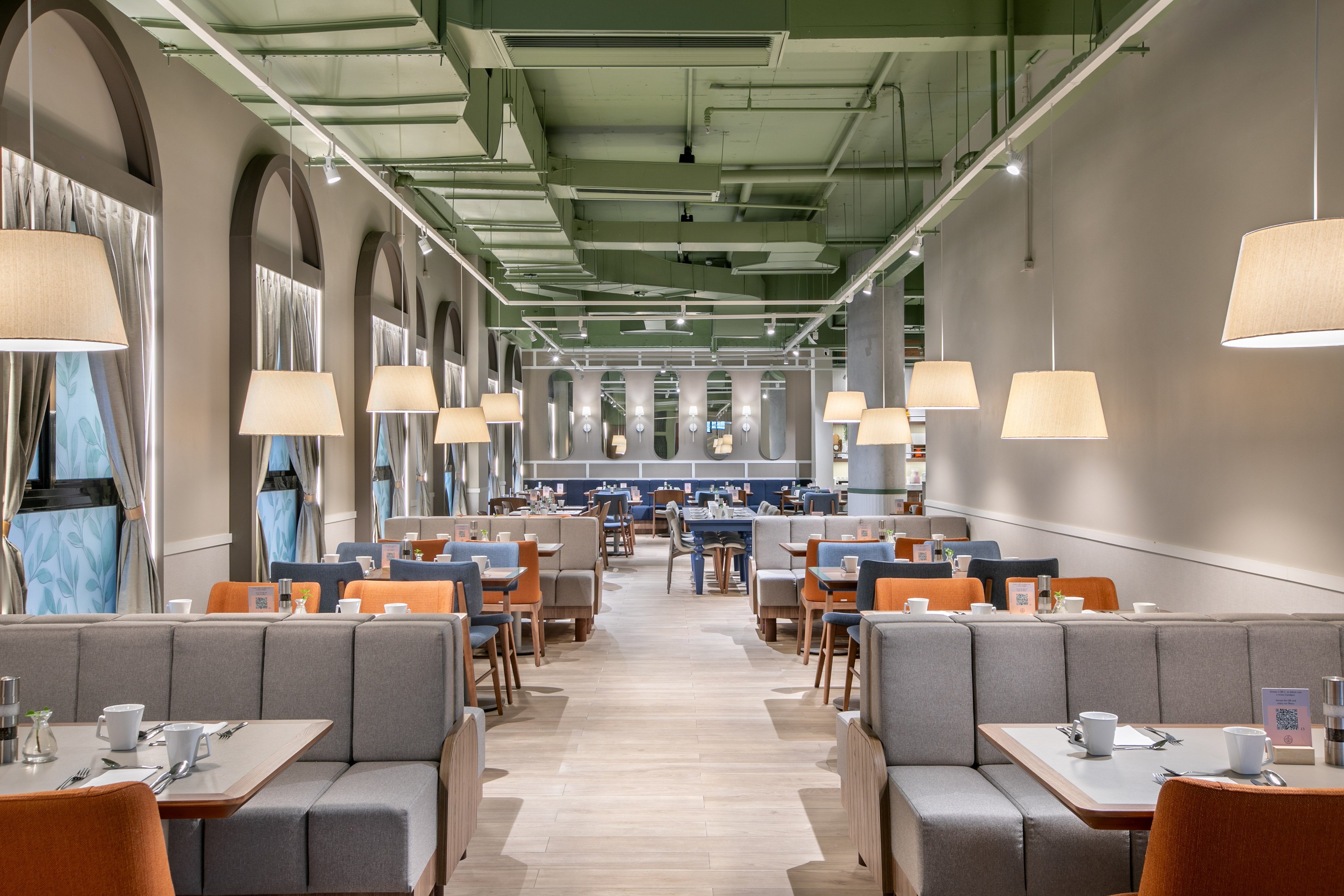 Spacious modern restaurant with booth seating, pendant lights, and green ceiling.